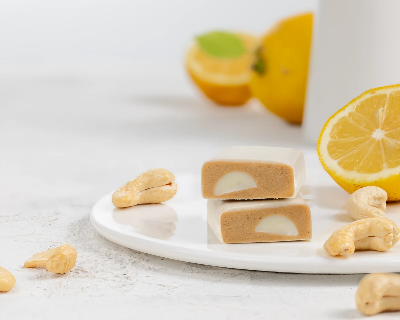 MojoBite lemon cookie protein bar with fresh lemon, cashews, and white filling visible on ceramic plate