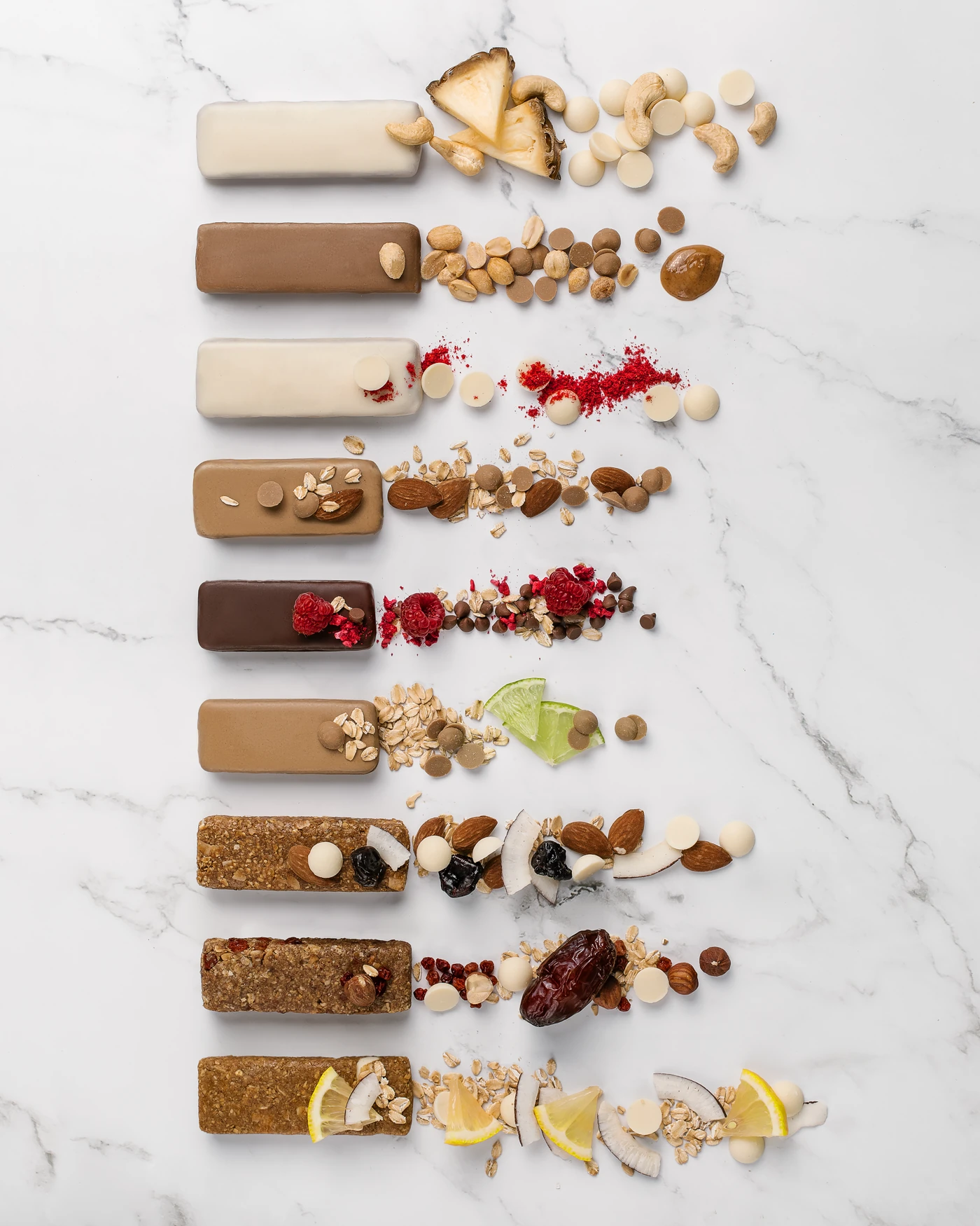 MojoBite nutritional bars full lineup with ingredient garnishes - nuts, berries, coconut, lemon, dates
