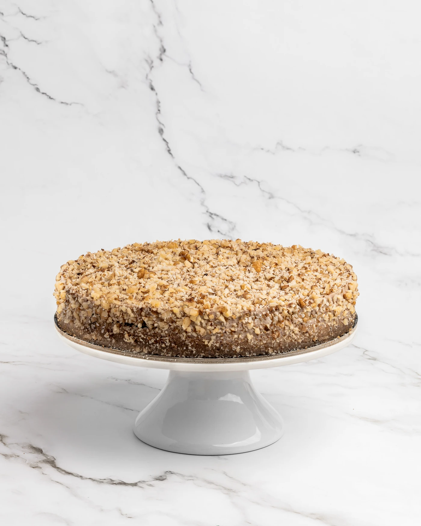 Walnut-topped whole cake on white pedestal - classic presentation