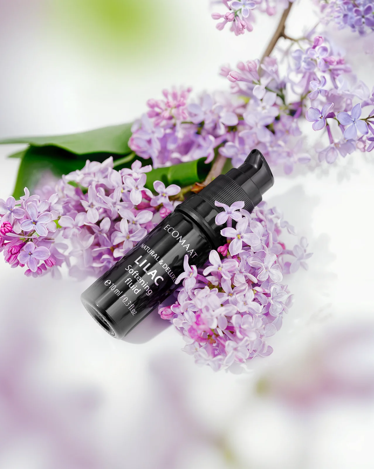 ECOMAAT Lilac fluid bottle nestled in fresh lilac blossoms