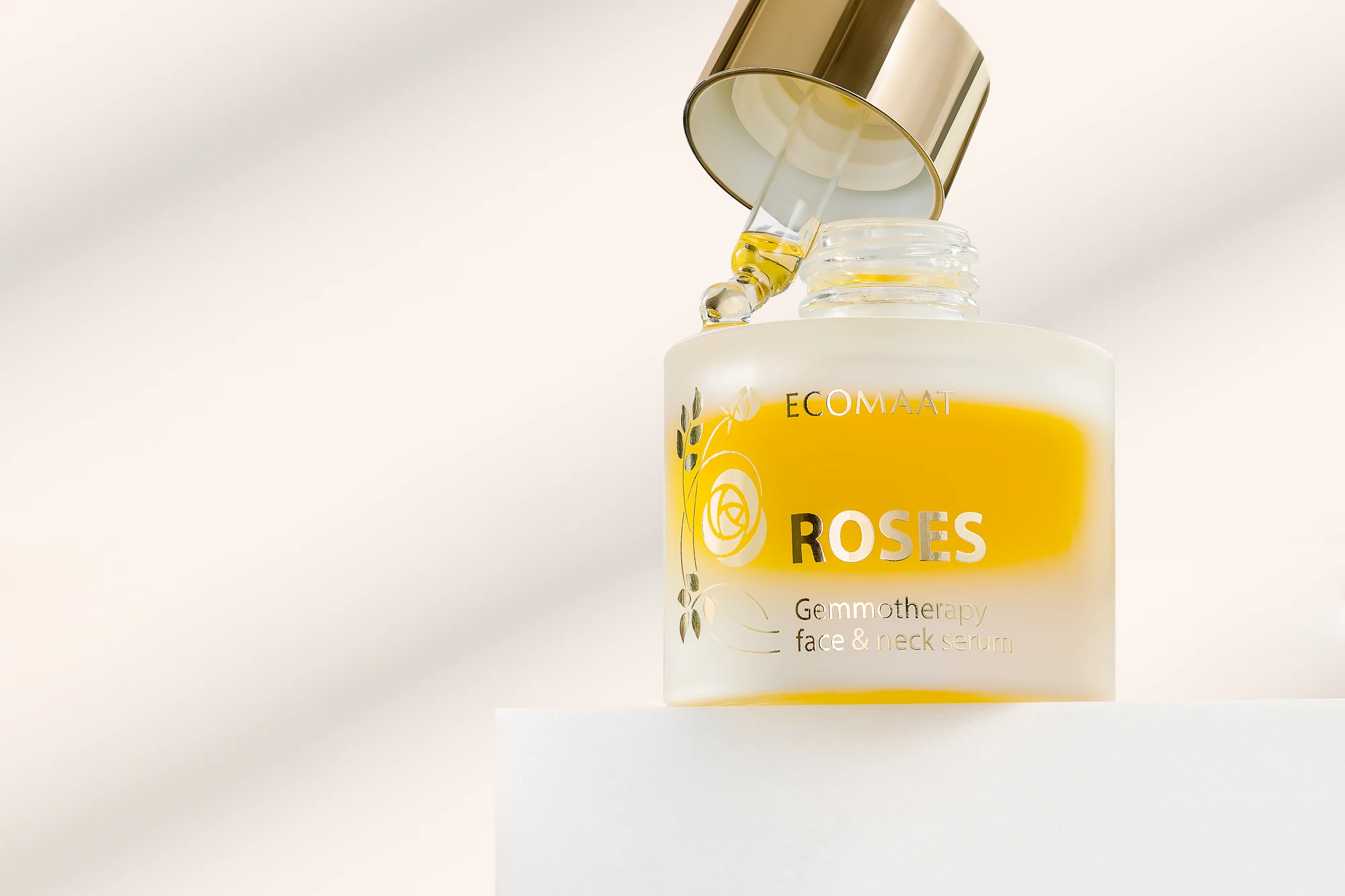 ECOMAAT Roses serum bottle with golden oil and soft shadow play