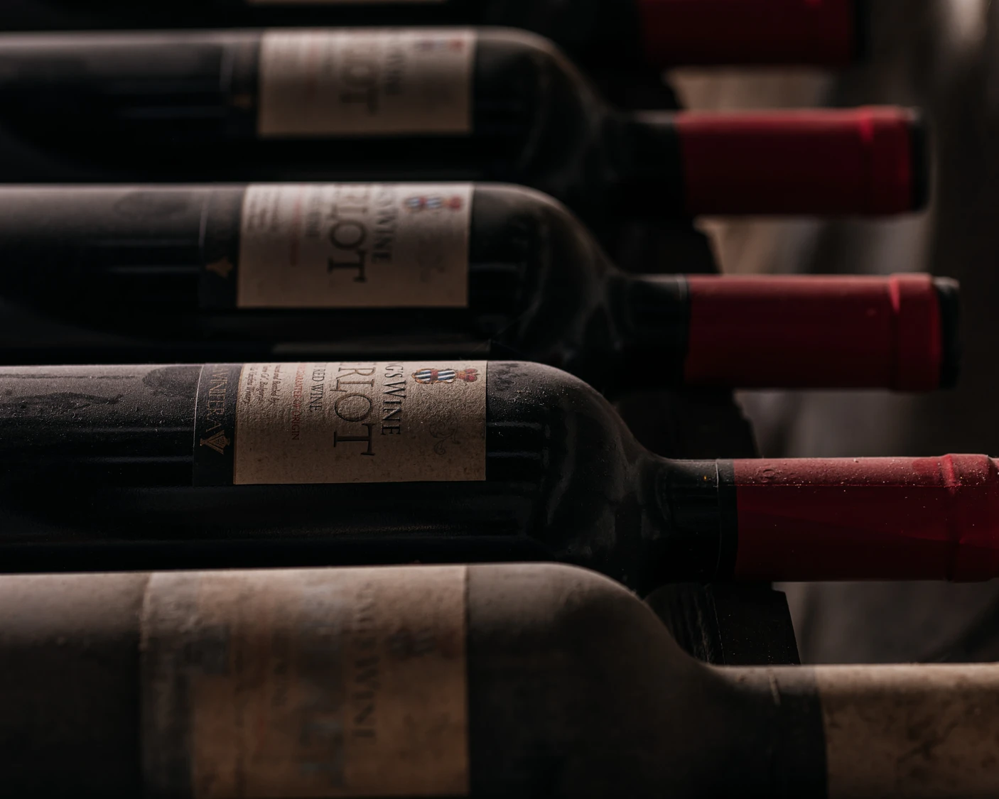 Прашни бутилки вино Мерло Вила Винифера на стелажи в българска винарска изба до Пловдив.