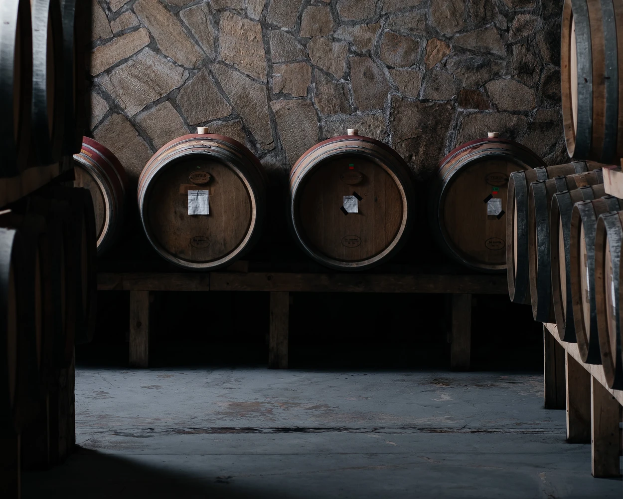 Големи винени бъчви отлежават в рустикална каменна изба на винарска изба Вила Винифера, Пловдив, България.