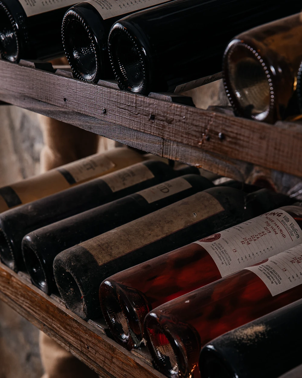 Вина Villa Vinifera, включително Розе Мавруд, на рустикални дървени стелажи в избата на българска винарна близо до Пловдив.