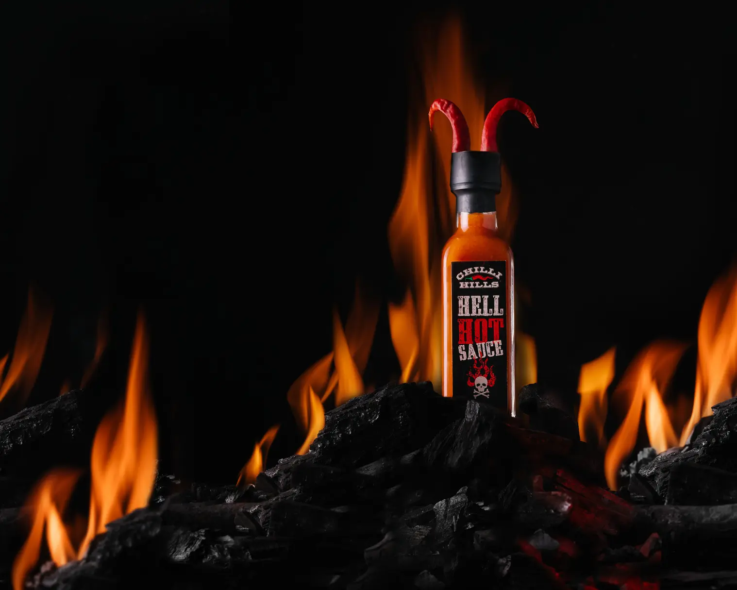 Бутилка Chilli Hills Hell Hot Sauce с чили рогца върху пламтящи въглени. Мастърклас Dynaphos огнени ефекти.