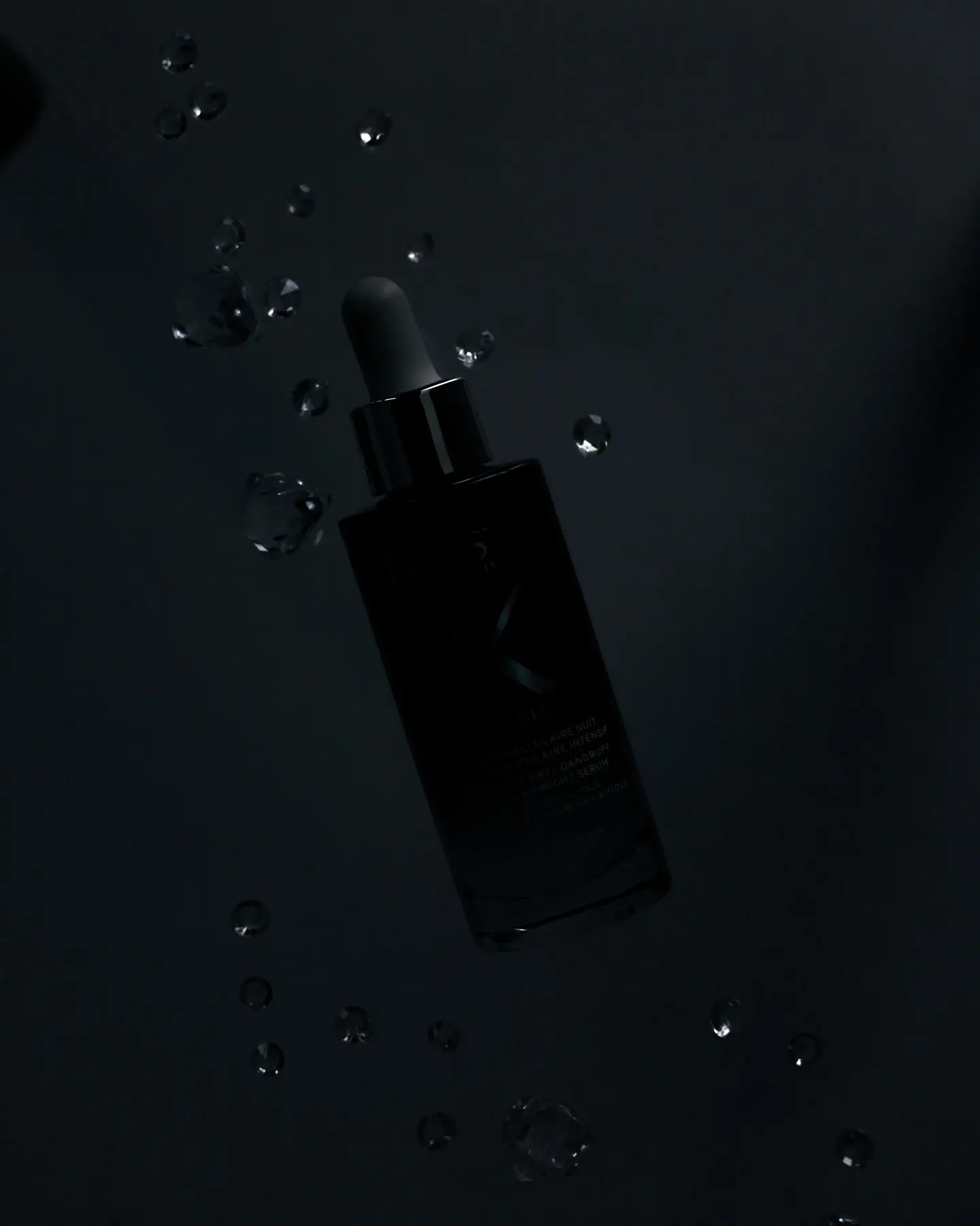 Levitating dark serum bottle with water drops, a Dynaphos special effects product photography master class technique.