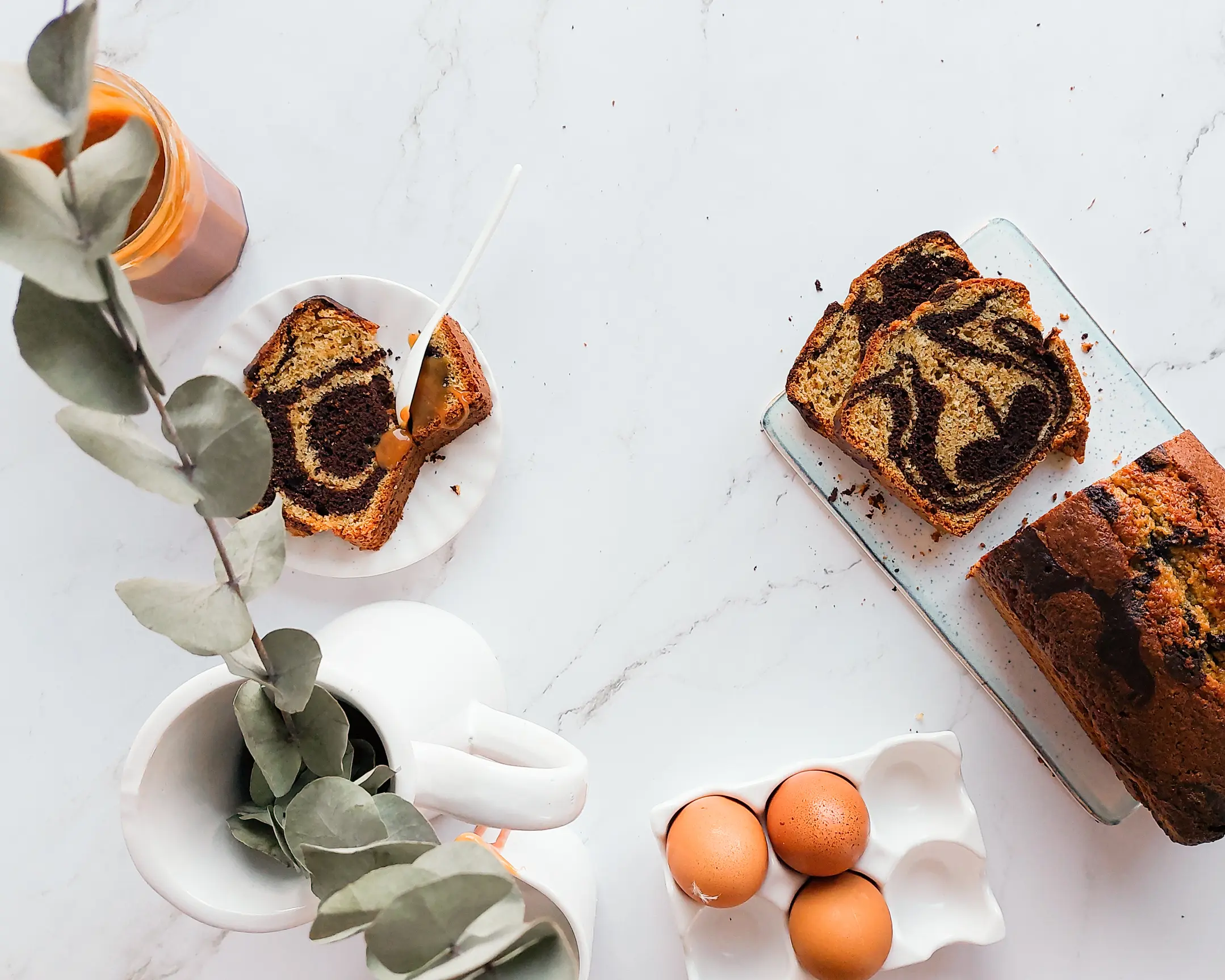 Стилизирана мраморна торта, карамел, яйца, евкалипт на бял мрамор за фантастична фото композиция на храна.