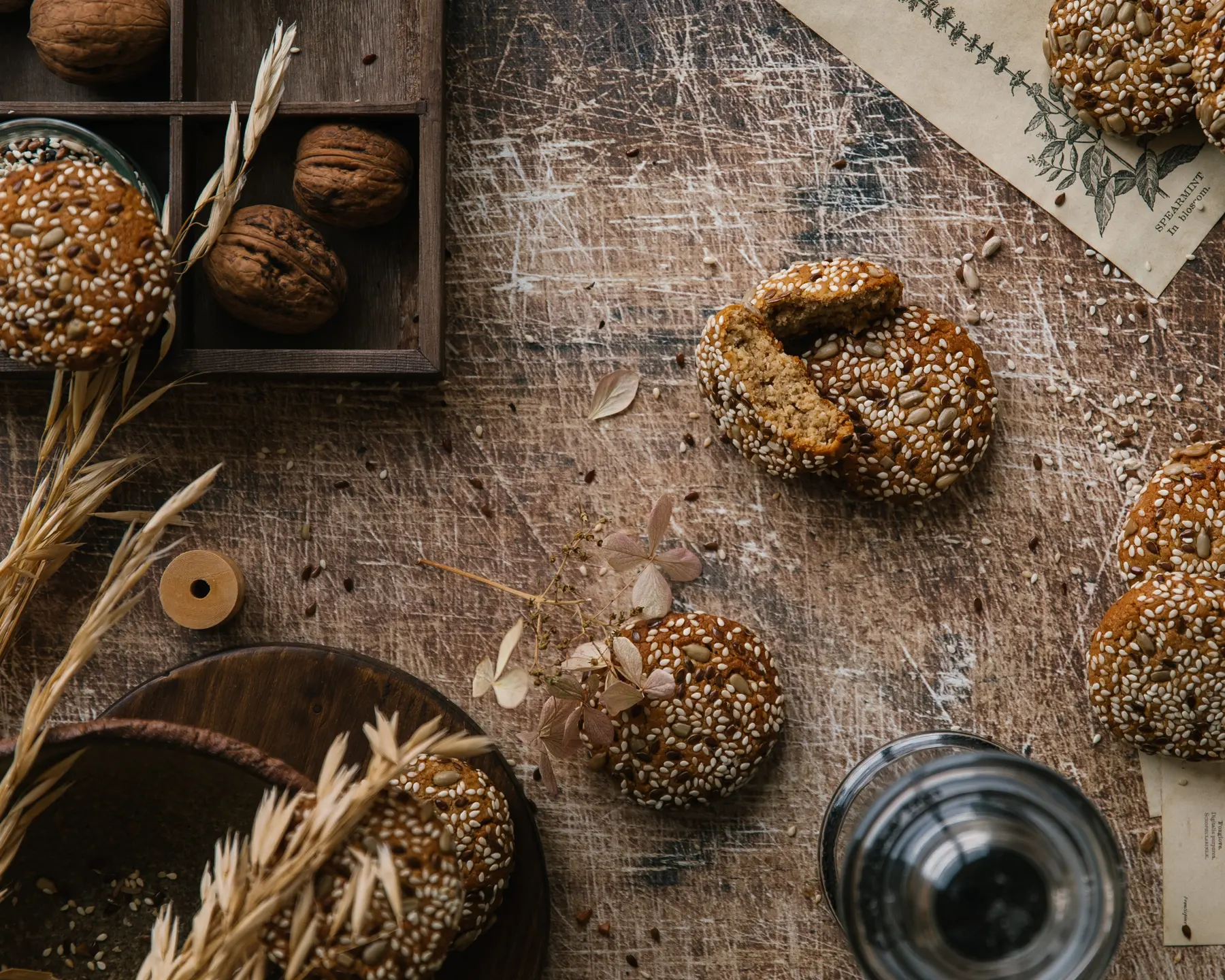 Стилна хранителна снимка отгоре: бисквити със семена, орехи и рустик реквизит върху дърво за фото композиция.