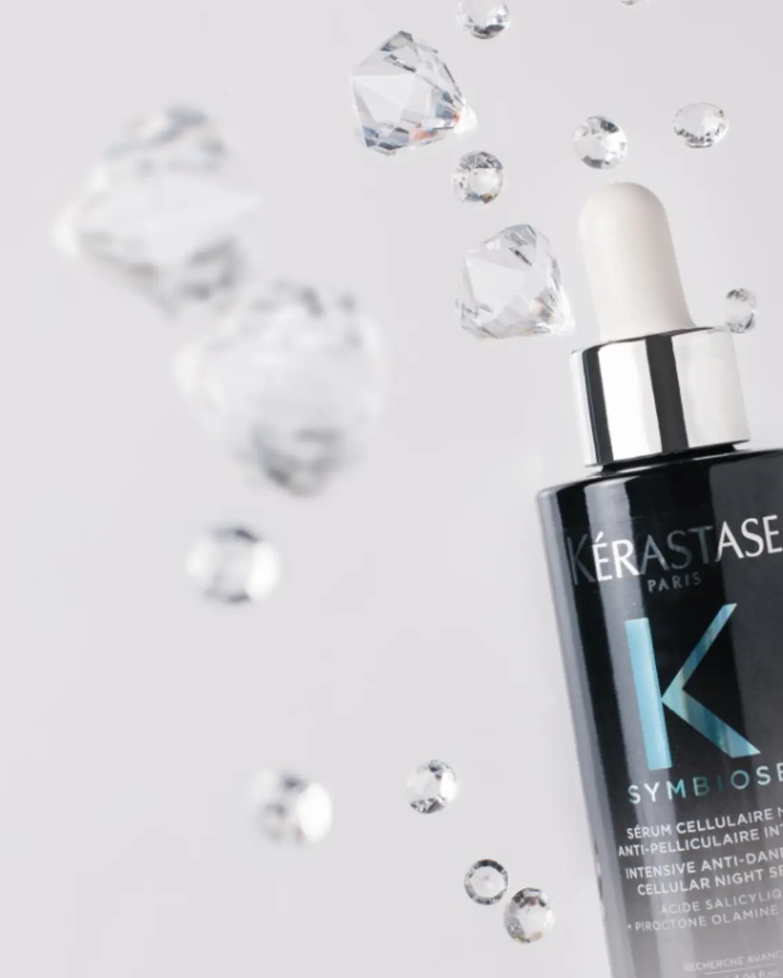 Kérastase Symbiose serum bottle with floating crystals, exemplifying glass product photography.