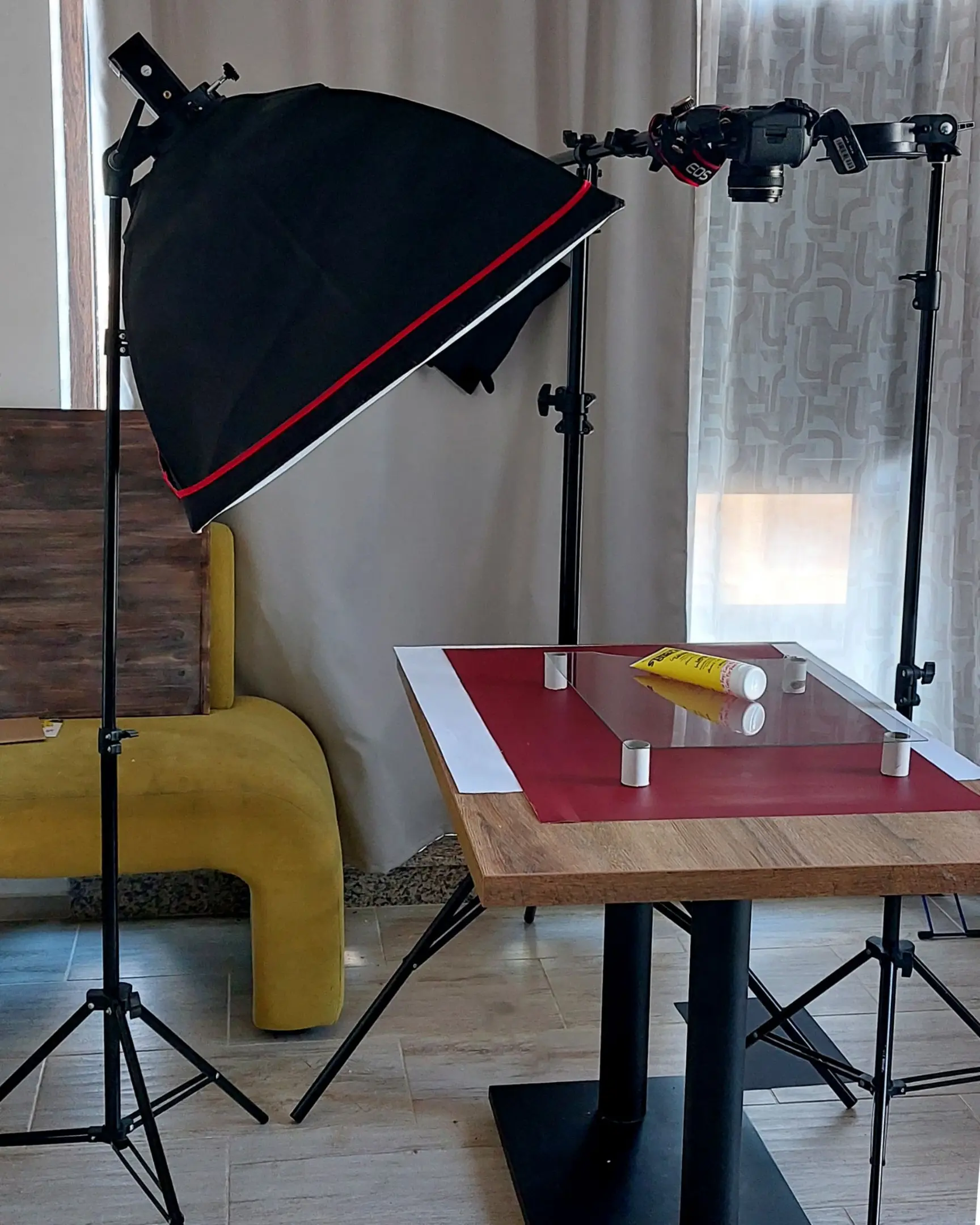 Product photography studio setup with glass for floating product effect; includes yellow tube, Canon EOS camera, softbox.