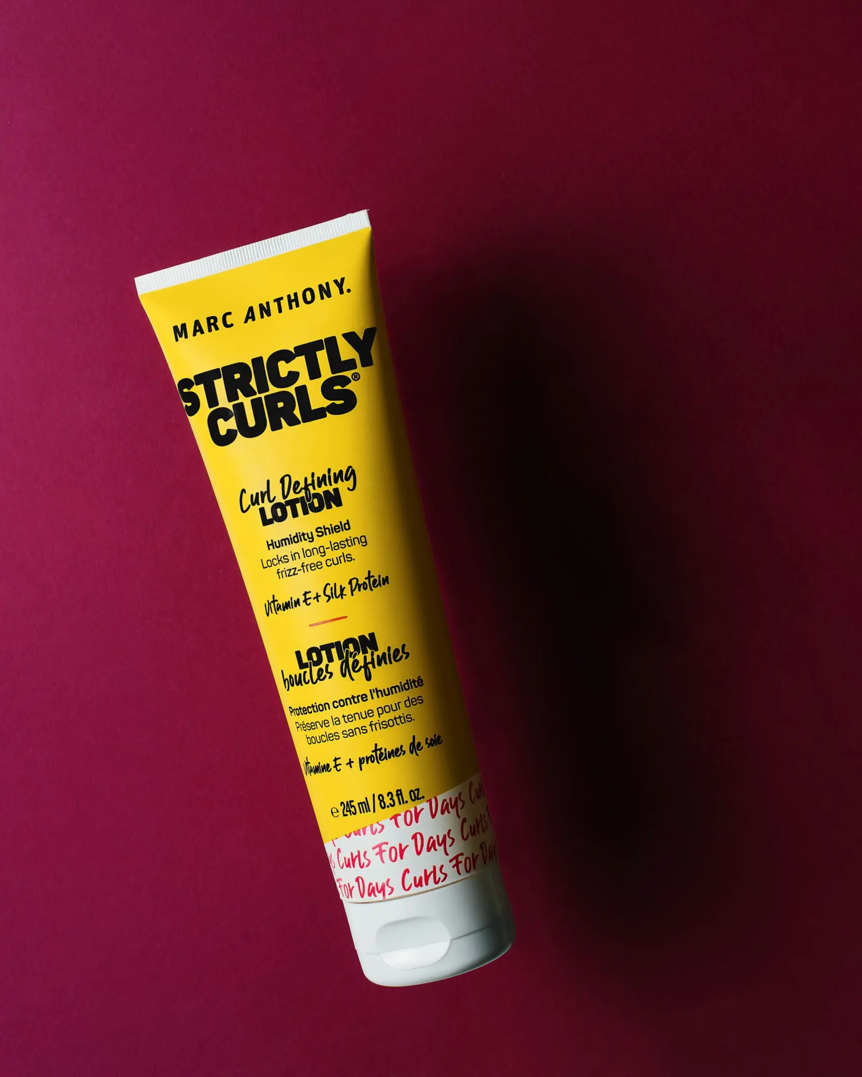 Marc Anthony Strictly Curls Curl Defining Lotion on red, illustrating product photography with glass.