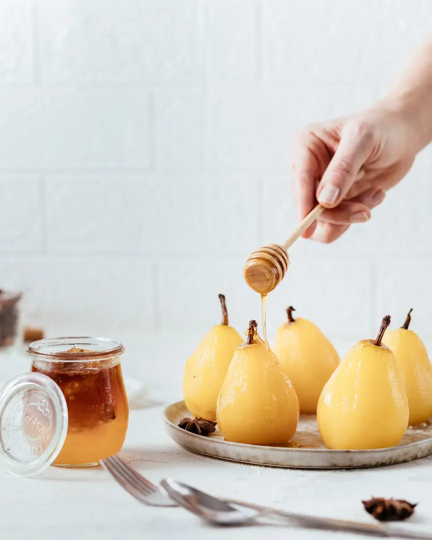Златни круши, поширани в бяло вино, поляти с мед – класически френски десерт на чиния.