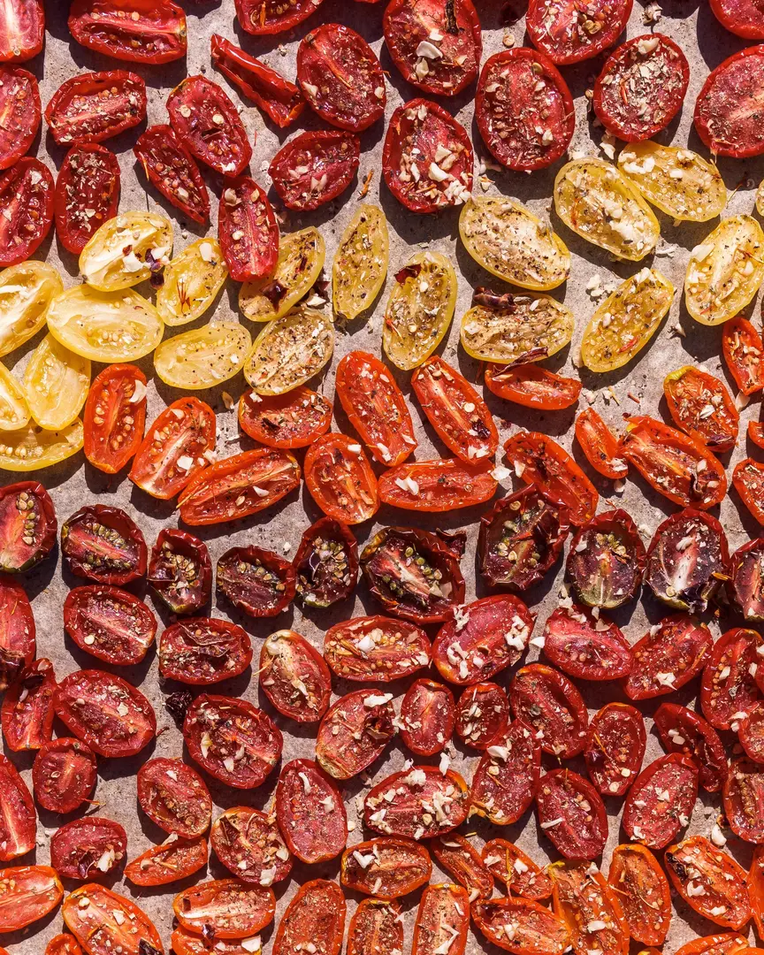 Prepared cherry tomato halves with garlic and herbs, sun-drying in Bulgaria.