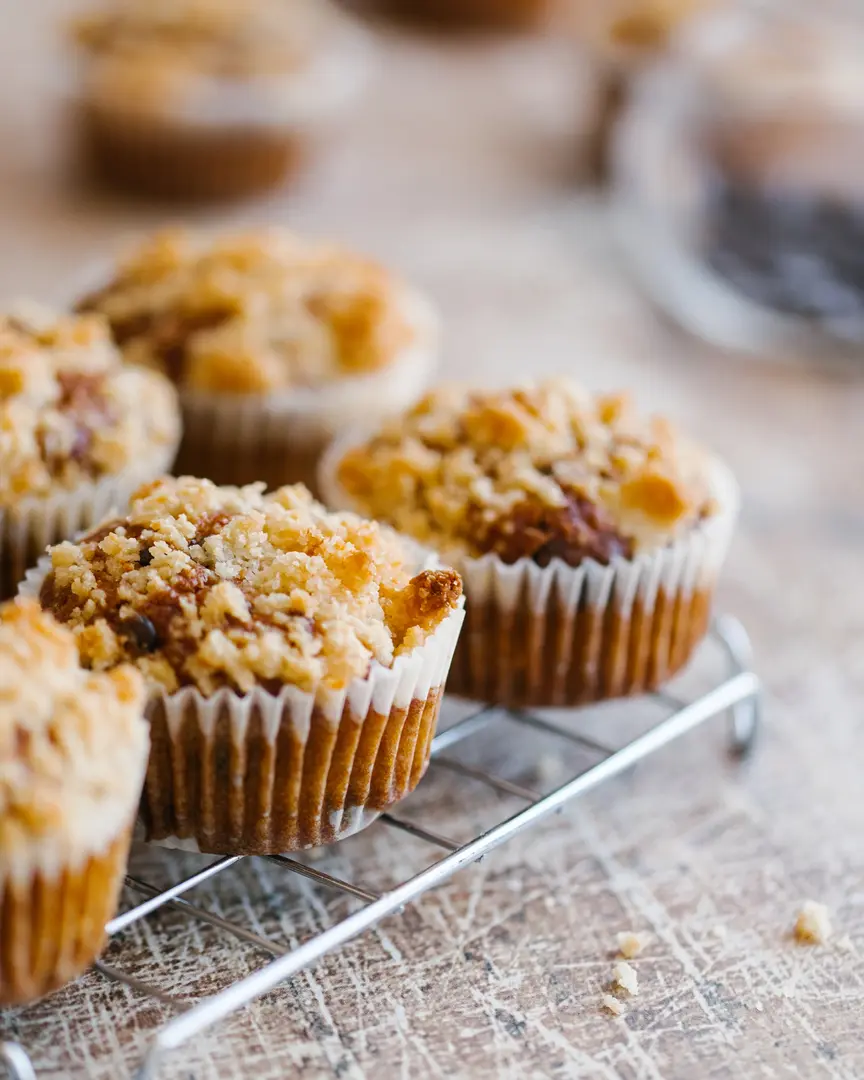 Golden pumpkin muffins with sweet crumble topping on a cooling rack, ready for a cozy fall treat.