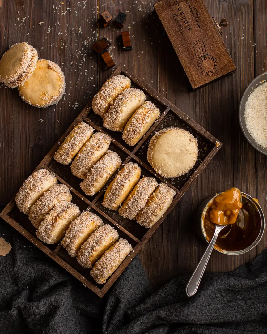 Домашни слепени бисквити, оваляни в кокос, с пълнеж от варено кондензирано мляко, в дървена табла.