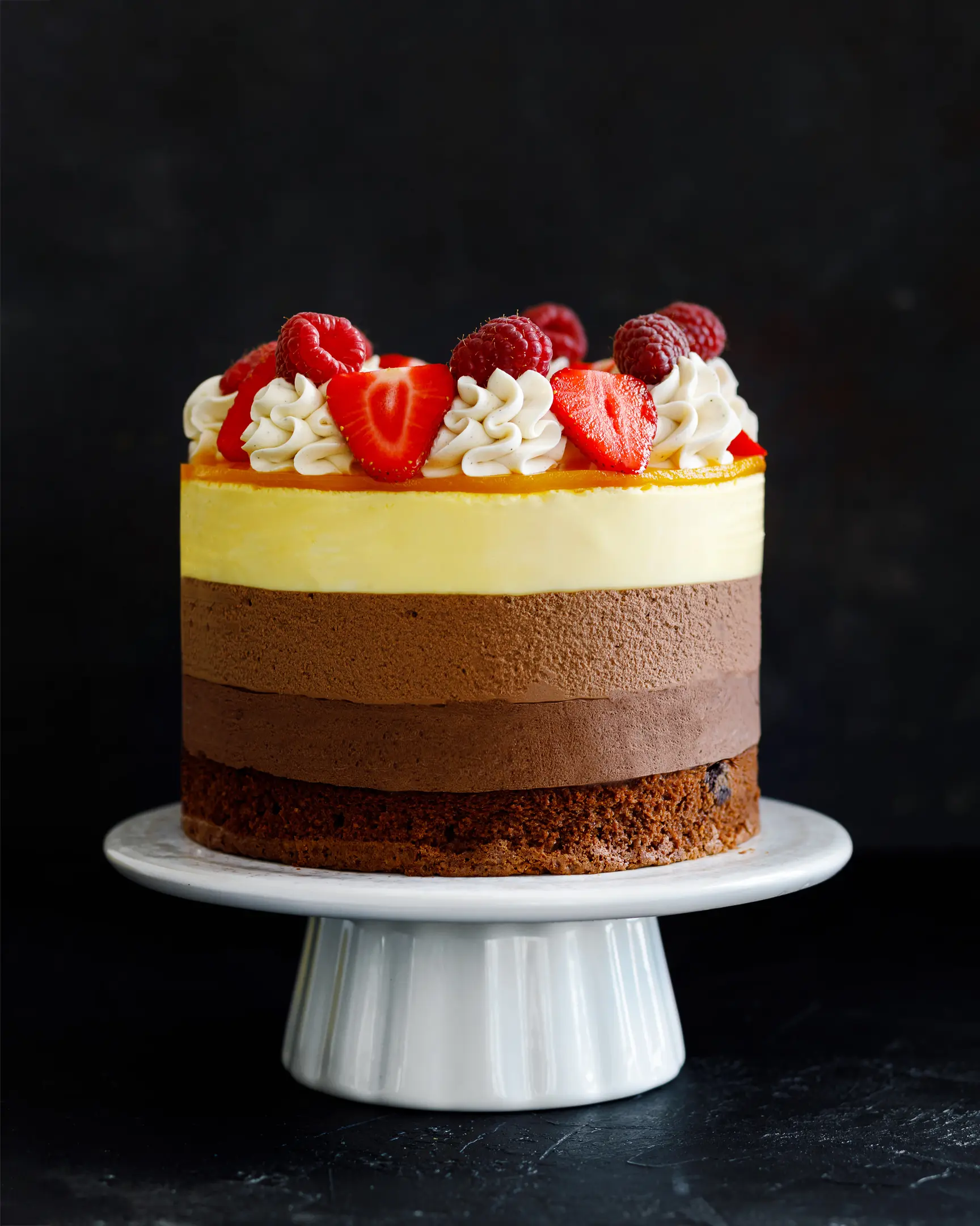 Triple Chocolate Mousse Cake with mango mousse, brownie base, garnished with strawberries, raspberries & cream.