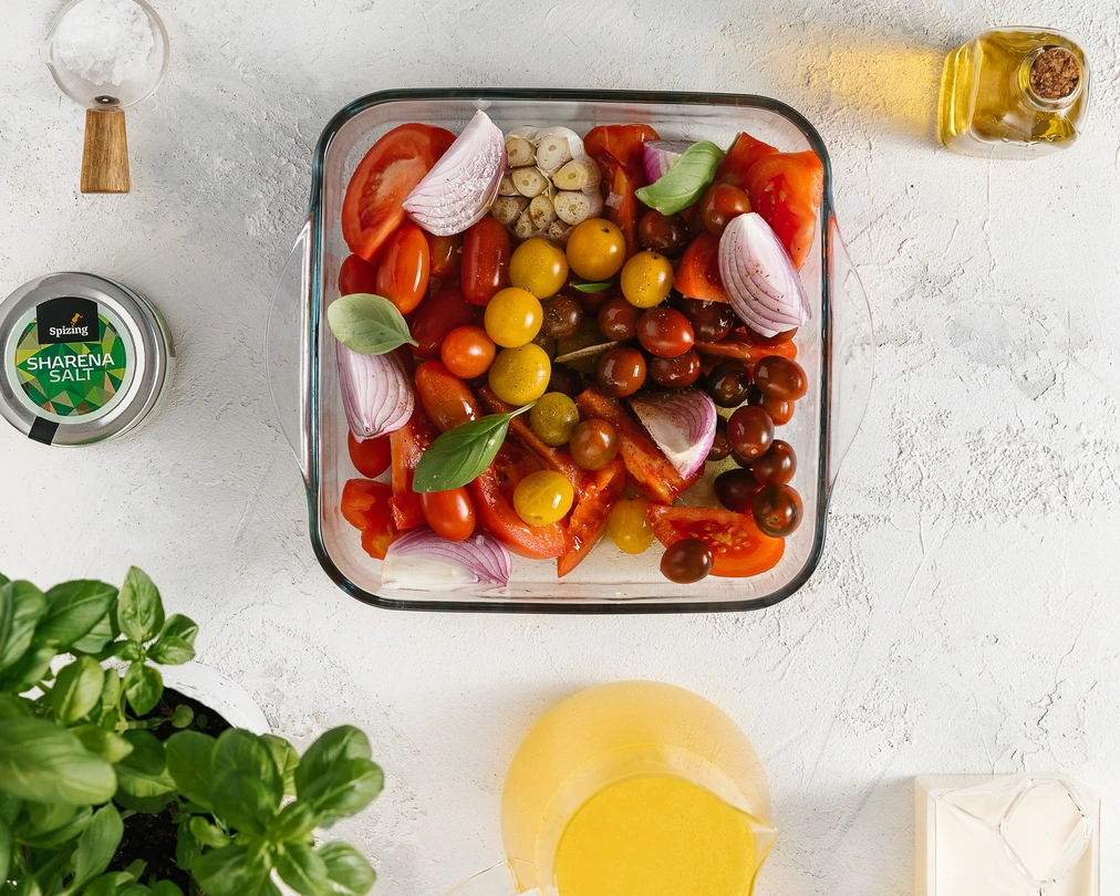 Tomatoes, red onion, garlic, basil, olive oil, & Spizing SHARENA SALT in a baking dish, ready for roasting for soup.