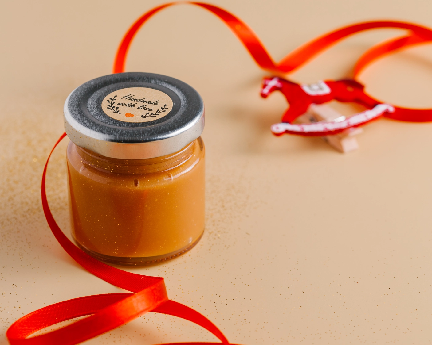 DIY Caramel Sauce jar with 'Handmade with love' label & red ribbon, ideal for homemade gifts.