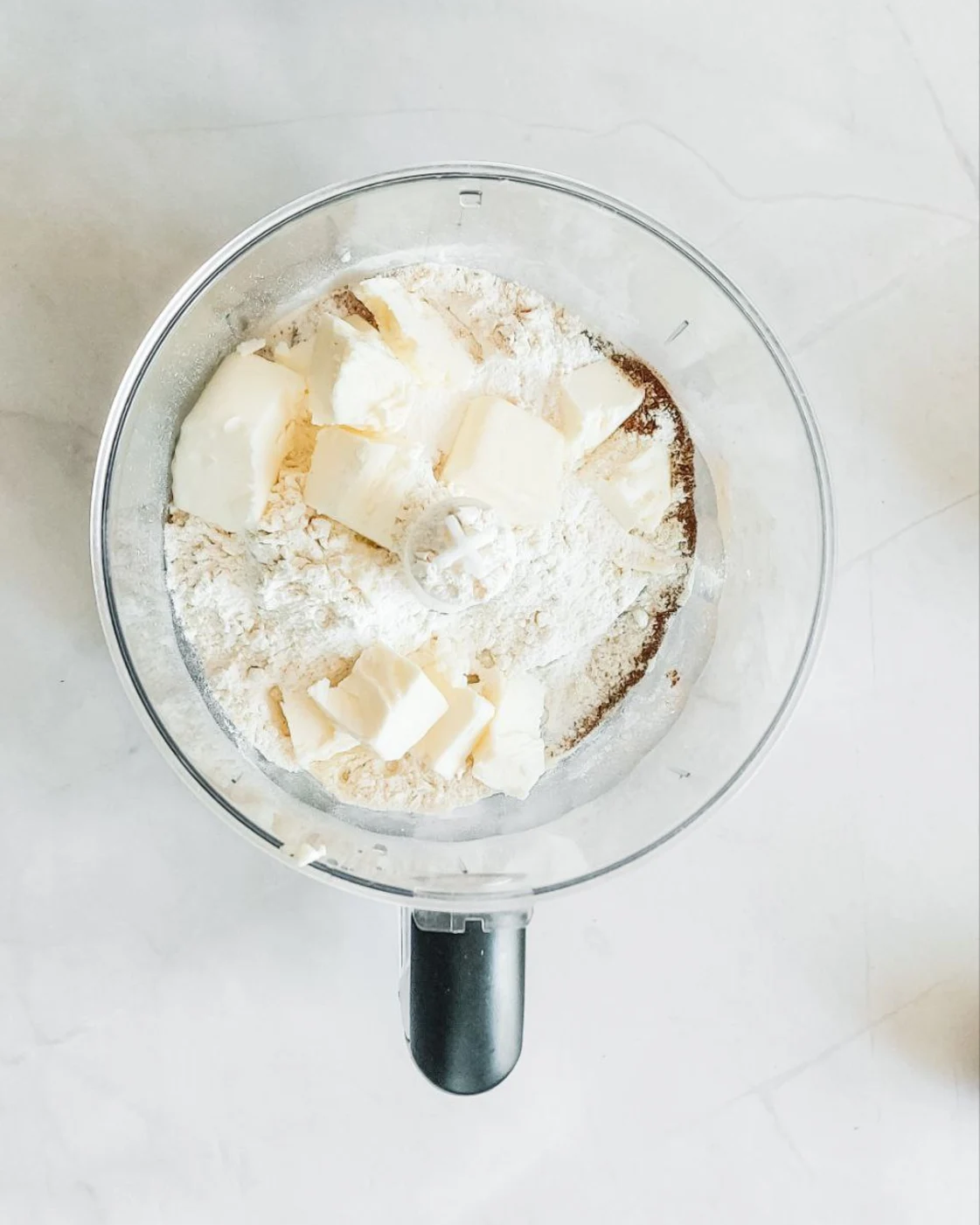 Смесване на студено масло, брашно, сол и подправки в кухненски робот за домашни тиквени скони.