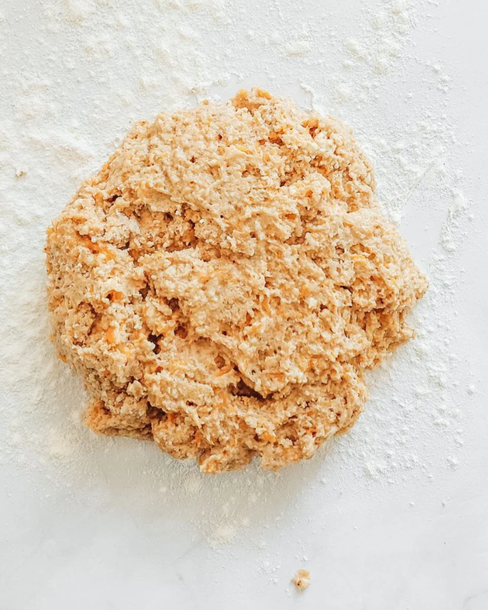 Меко, лепкаво тиквено тесто за скони върху набрашнена повърхност, готово за оформяне за есенни печива.