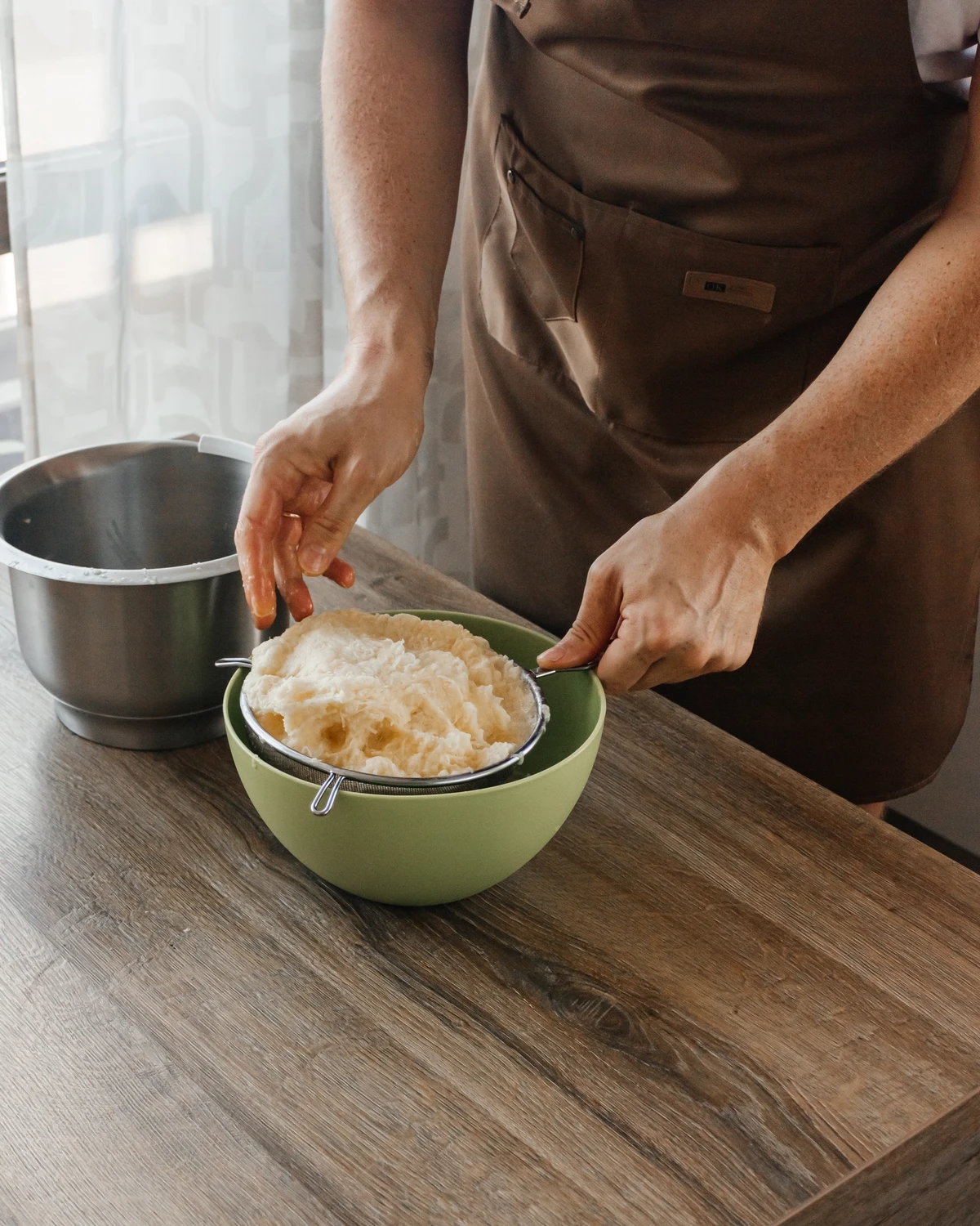 Person straining grated raw potatoes for Belarusian potato babka or Jewish Kugel casserole.