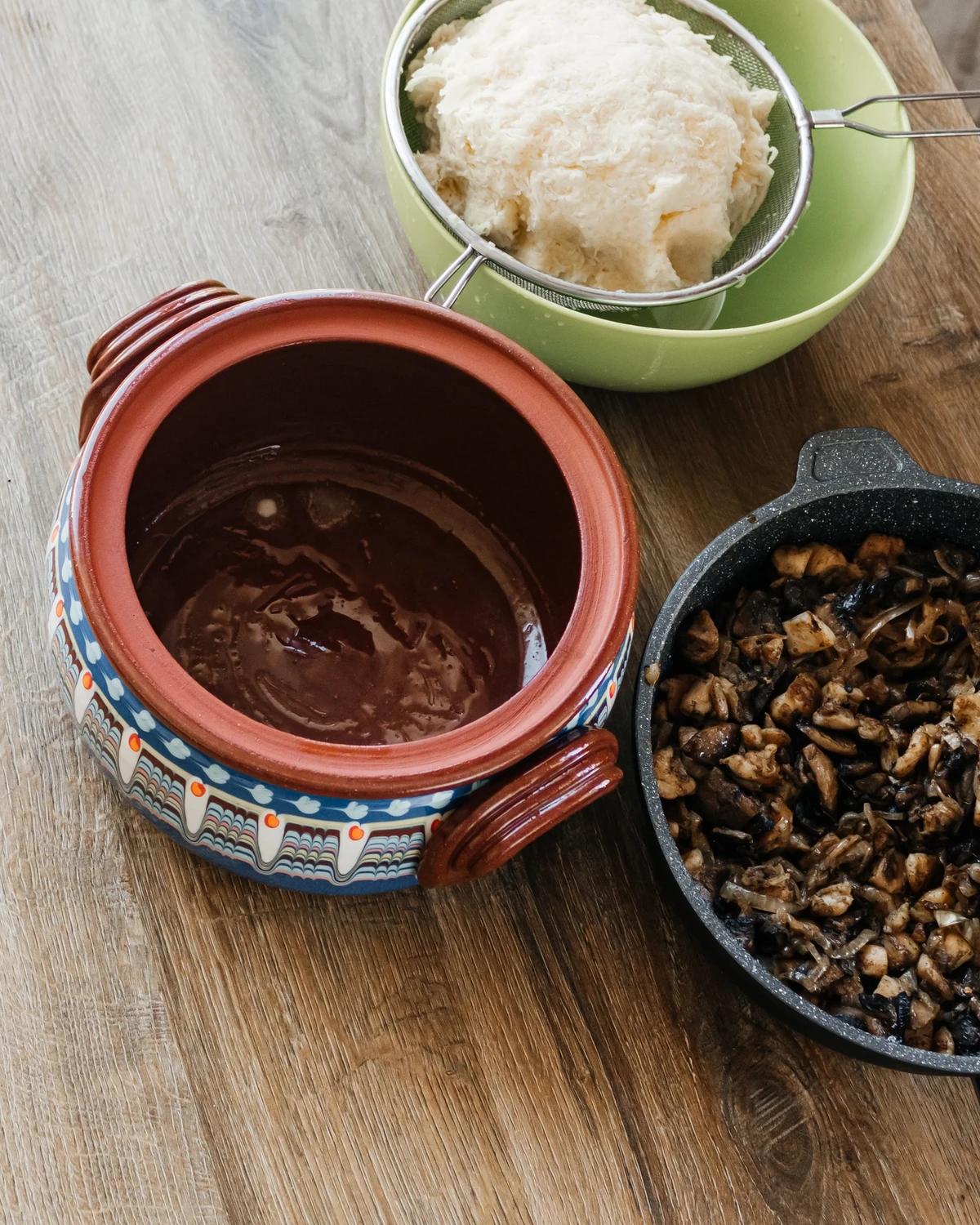 Potato babka (Kugel) preparation: grated potatoes, fried mushrooms & onions, and a traditional clay baking pot.