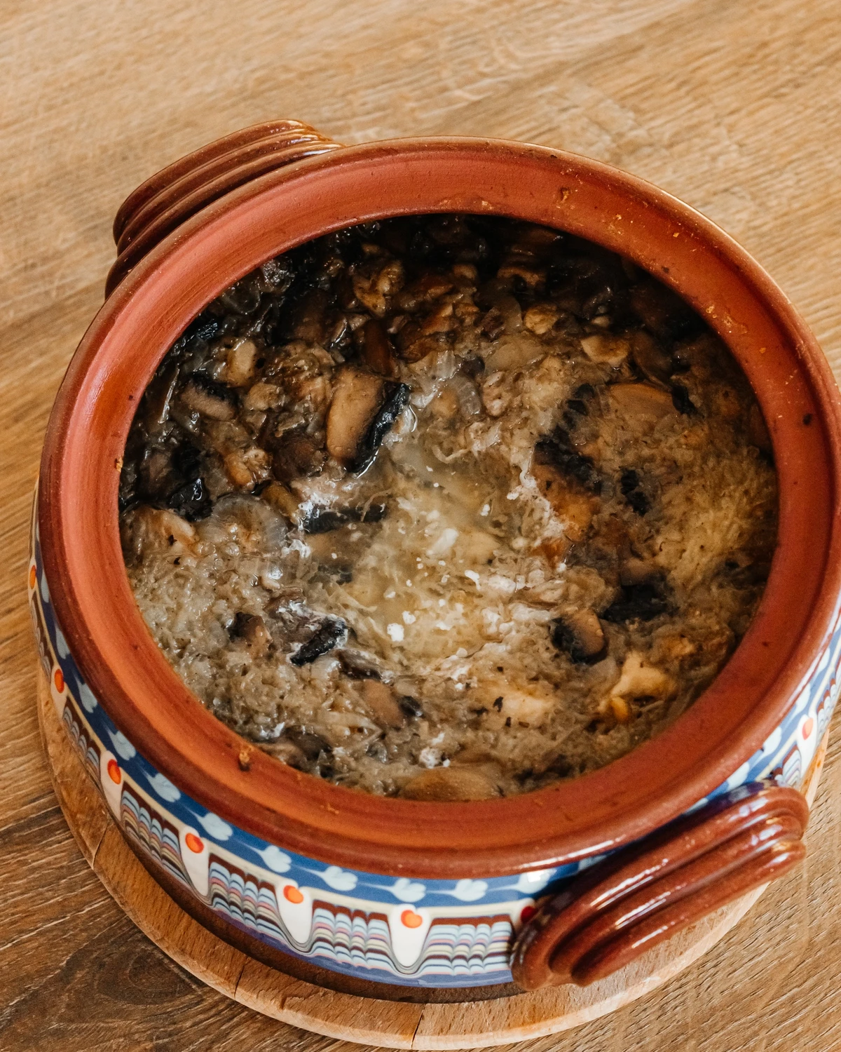 Belarusian potato kugel (Bulbyanaya grandmother) with mushrooms in a traditional decorated clay pot.