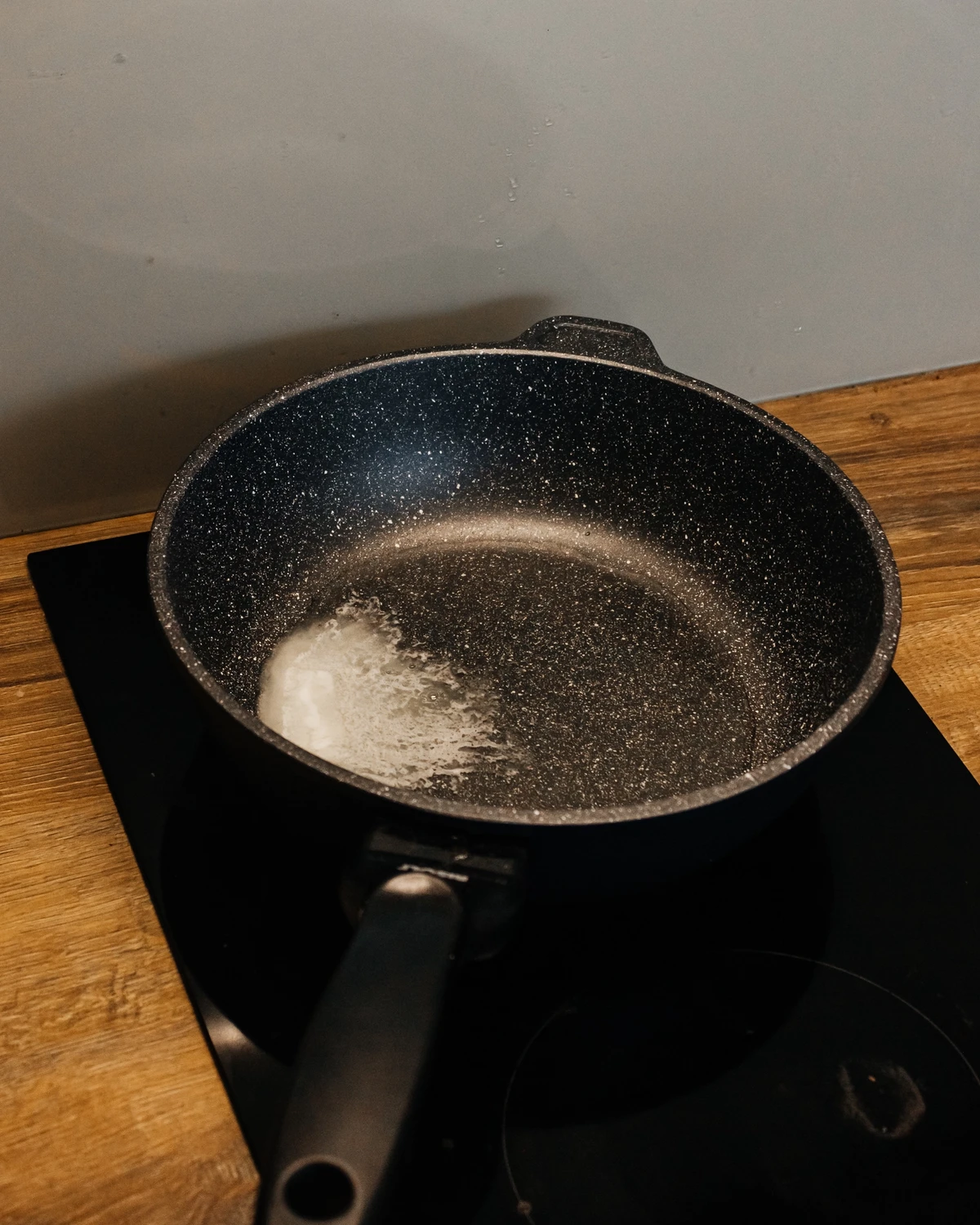 Melting butter in pan on induction stove for Belarusian potato babka (kugel) with mushrooms & meat.