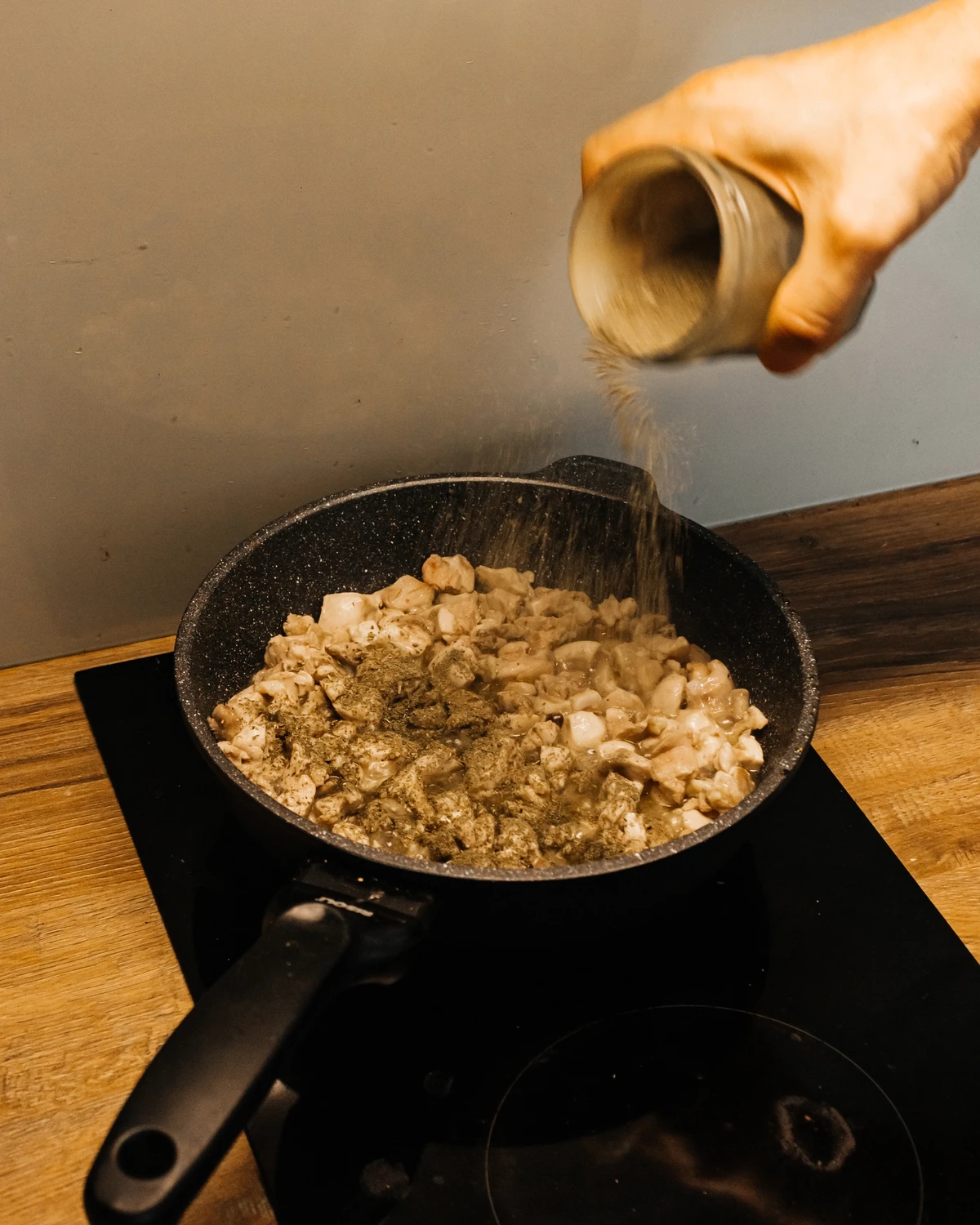 Seasoning chopped chicken and mushrooms in a pan for a traditional potato babka or Kugelis recipe.