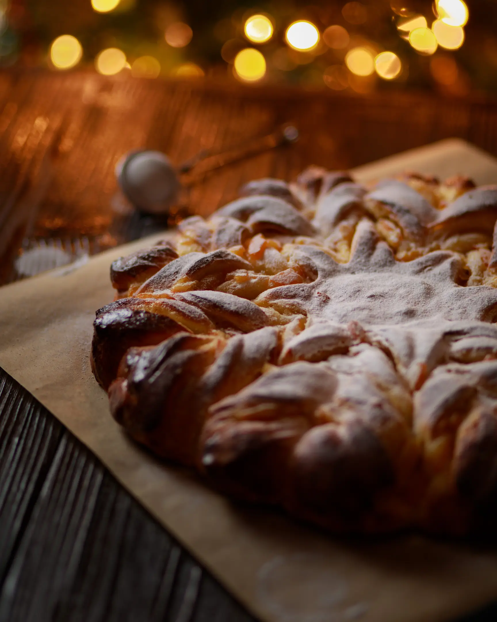 Golden star-shaped pie, powdered sugar, filled with orange peel jam. Recipe highlight on a rustic wooden table.