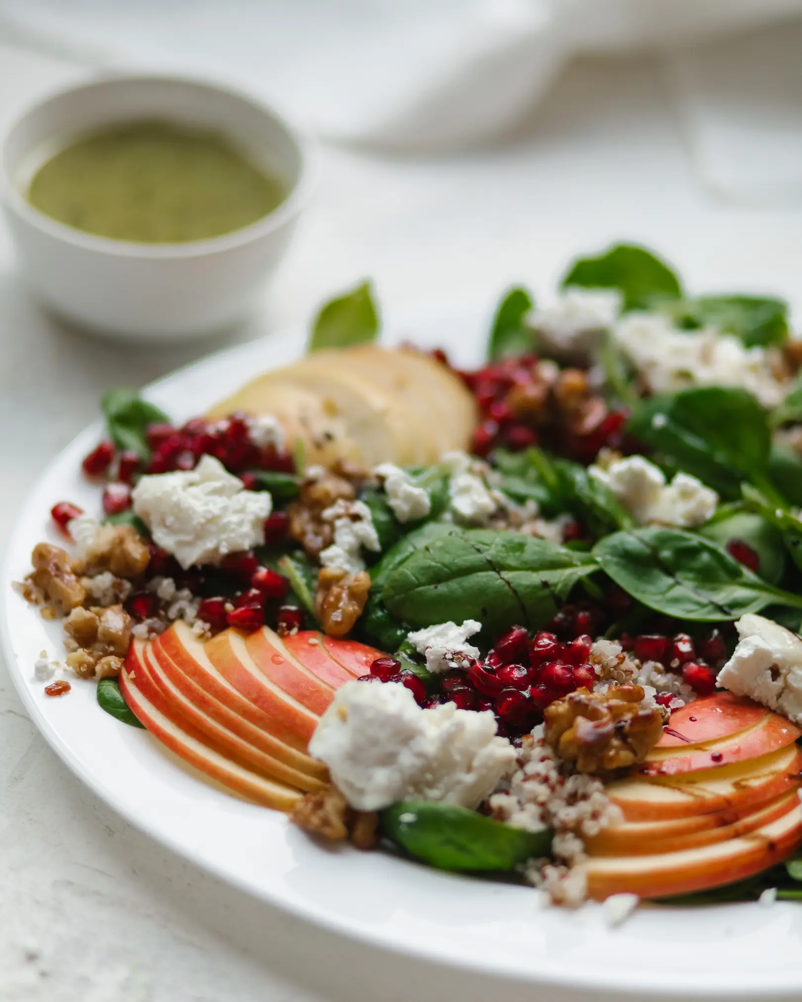 Quinoa salad with spinach, sliced apple, pomegranate, goat cheese, caramelized walnuts, and sweet mustard dressing.