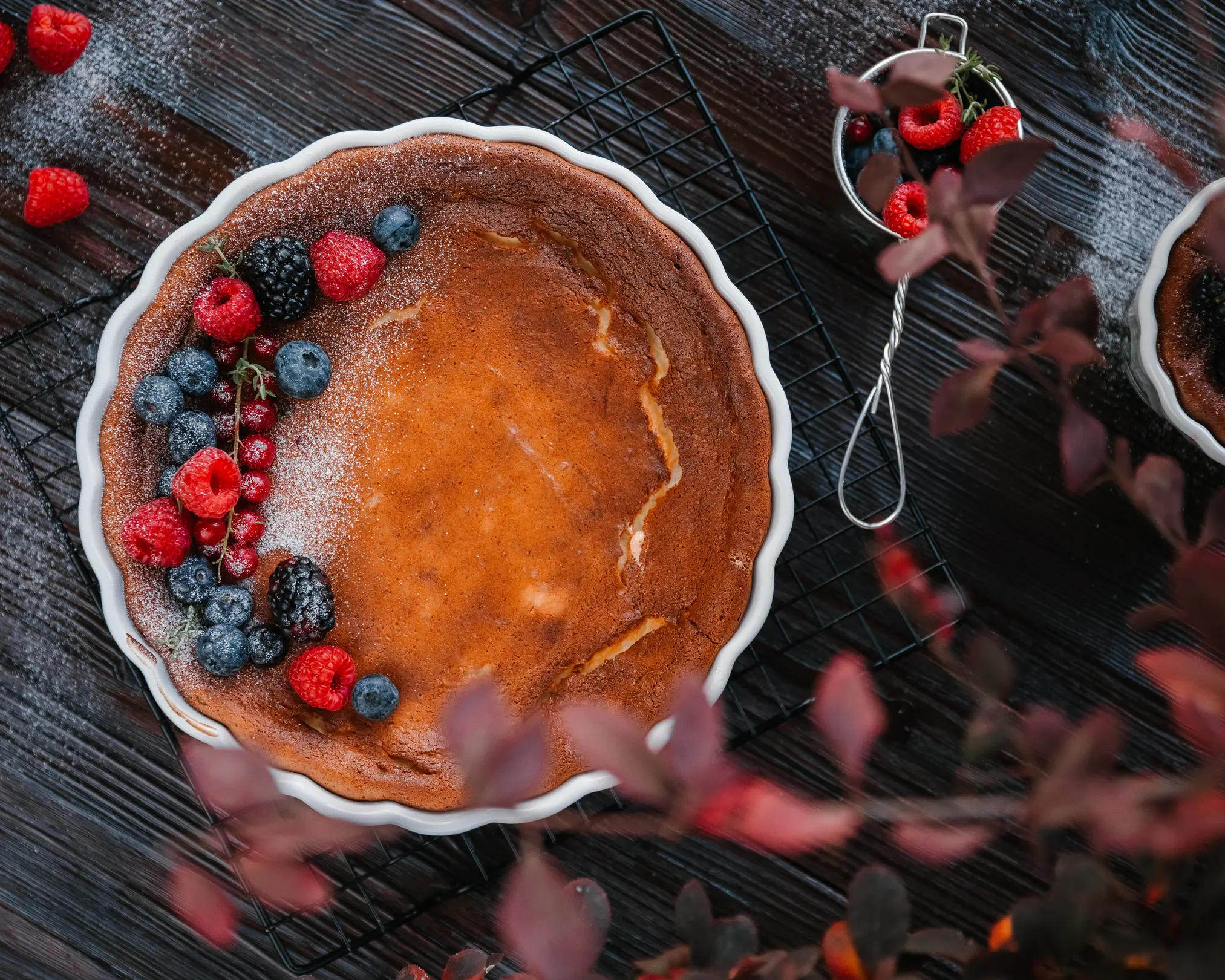 Golden sweet cottage cheese casserole with fresh raspberries, blueberries, and red currants, dusted with sugar.