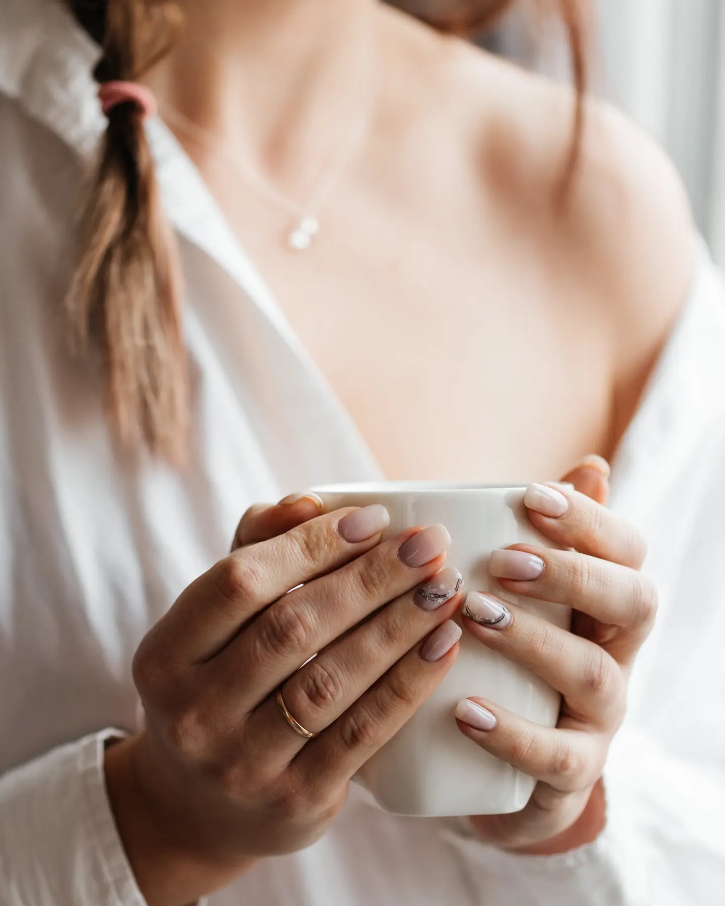 Woman holding a warm mug, ideal for savoring fresh Oatmeal Cranberry Cookies from the recipe.