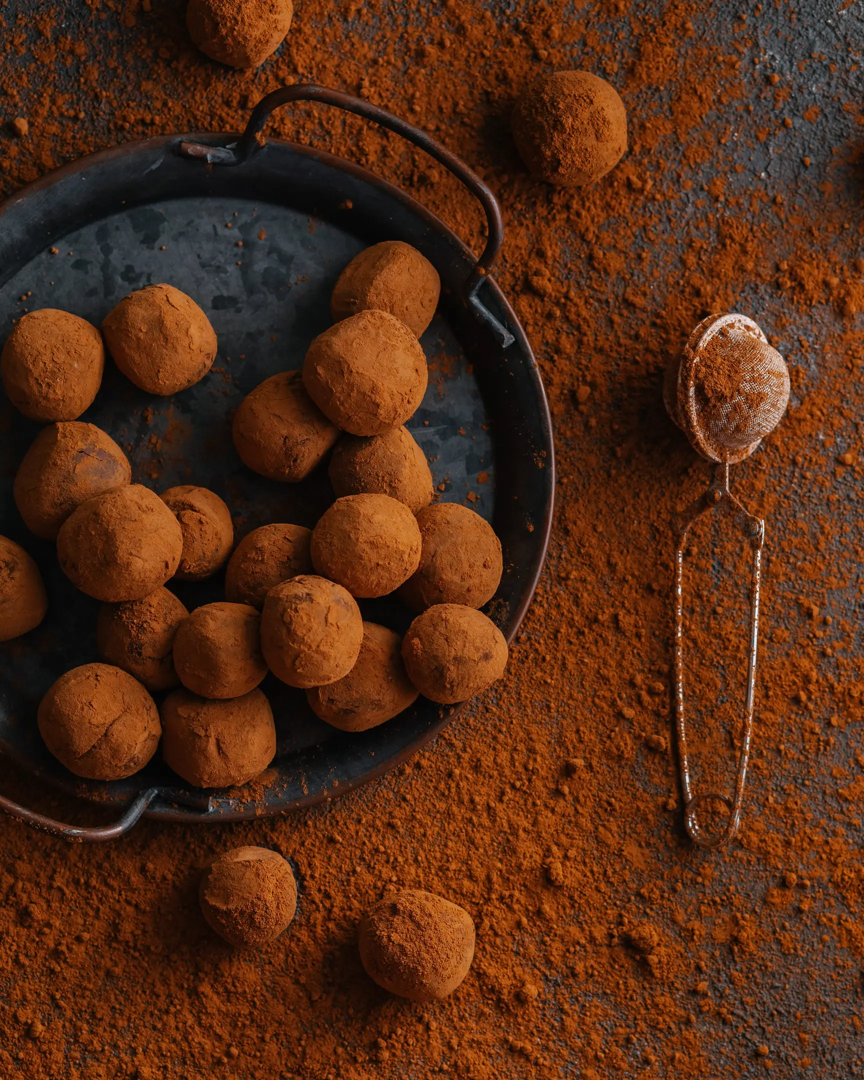 Богати шоколадови трюфели с еспресо и ванилия, поръсени с какао на прах, на поднос.