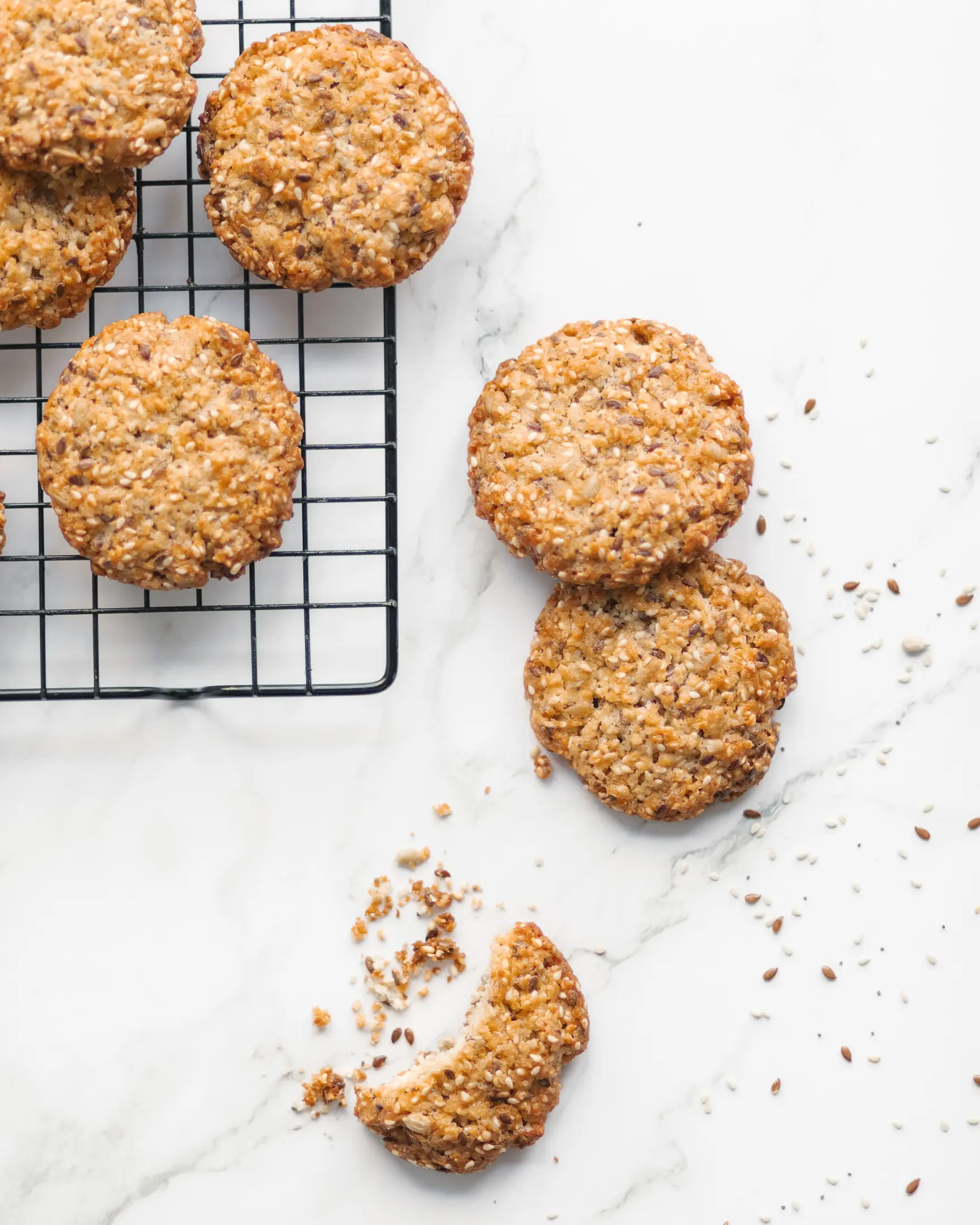 Златисти курабийки със сусам, мак и слънчогледови семки, на решетка и мрамор; счупена курабийка.