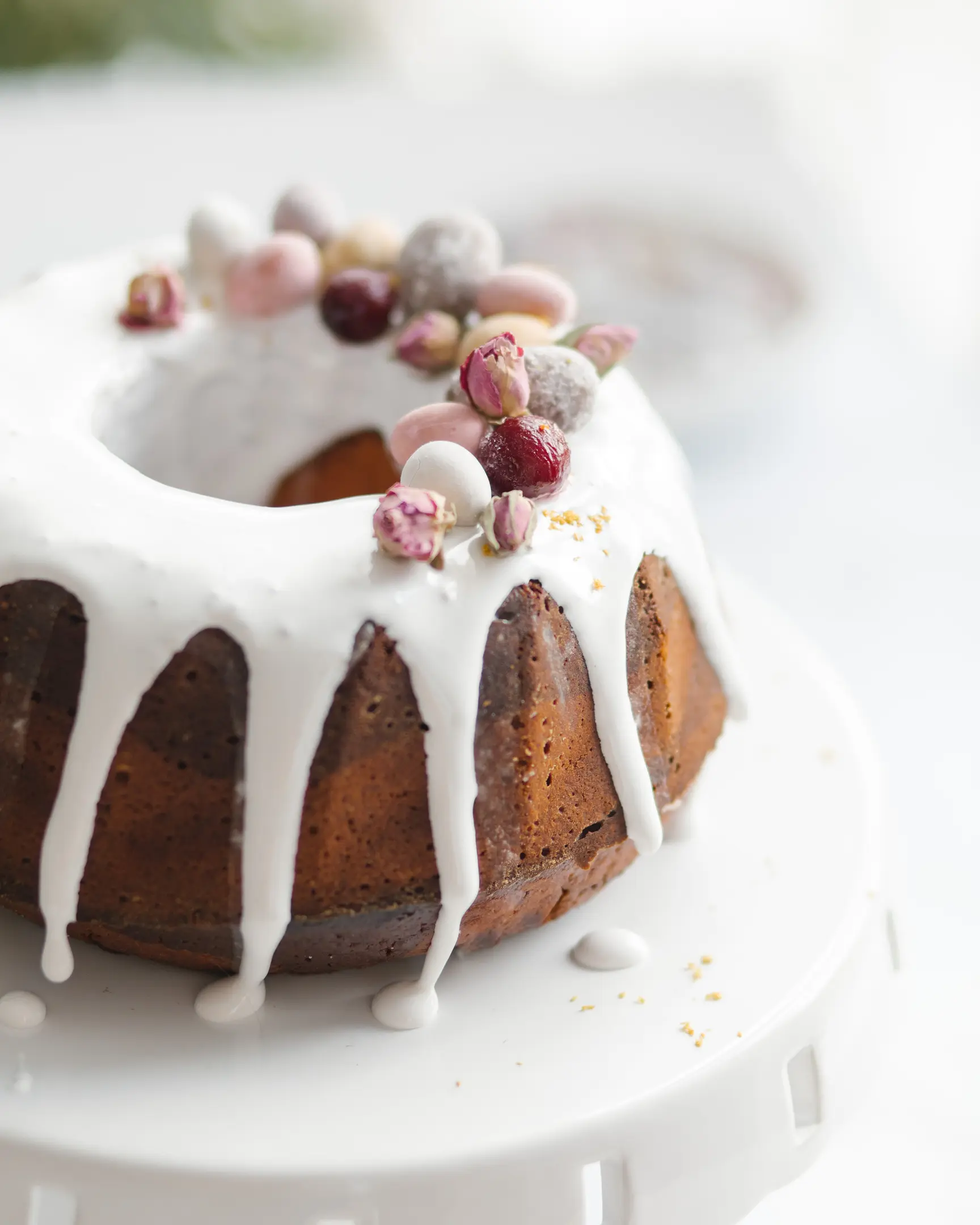 Сочен портокалов блендер кекс с бяла глазура, декориран с шарени бонбони и розови пъпки.