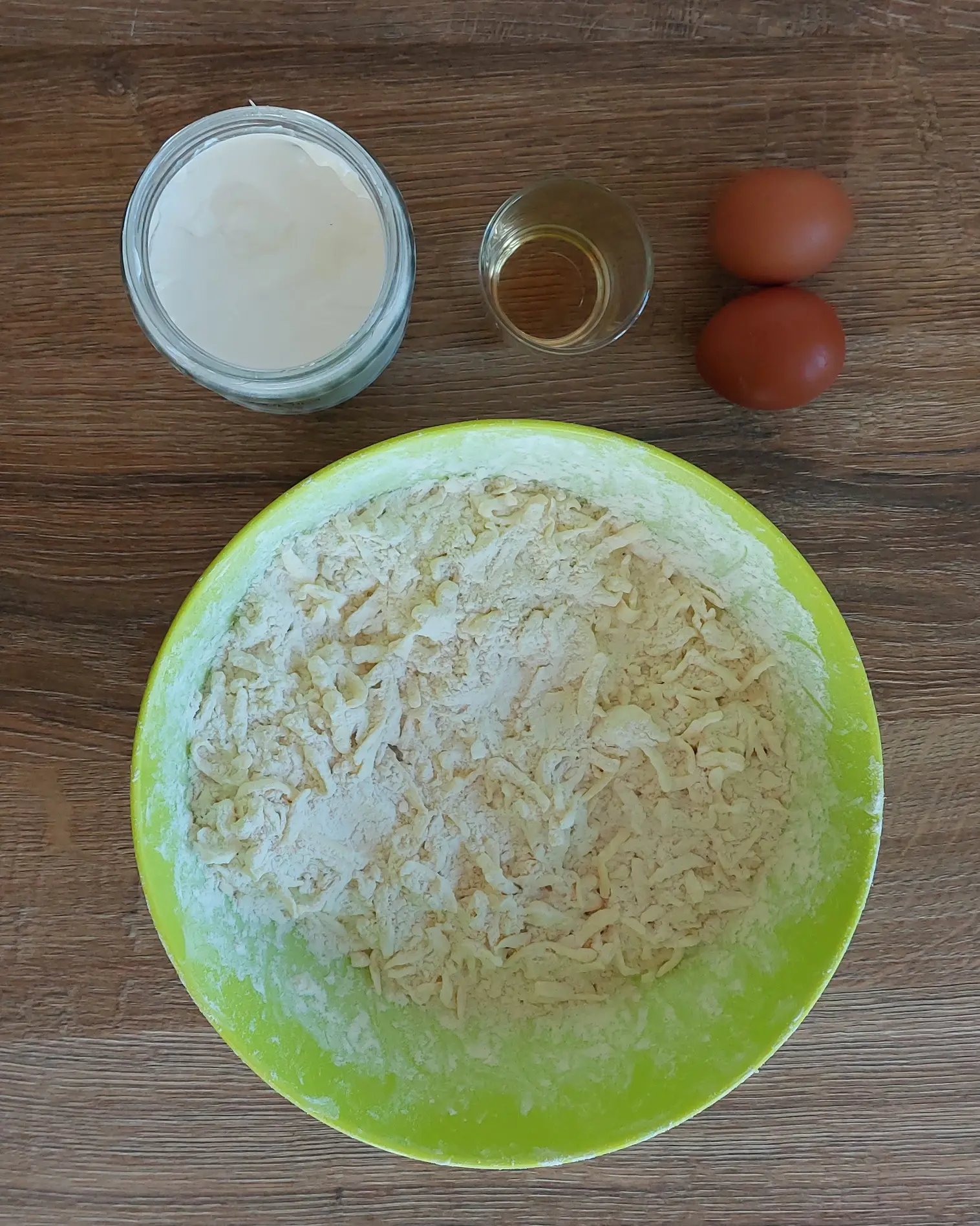 Съставки за многолистно тесто: настъргано масло с брашно в зелена купа, заквасена сметана, яйца и алкохол.