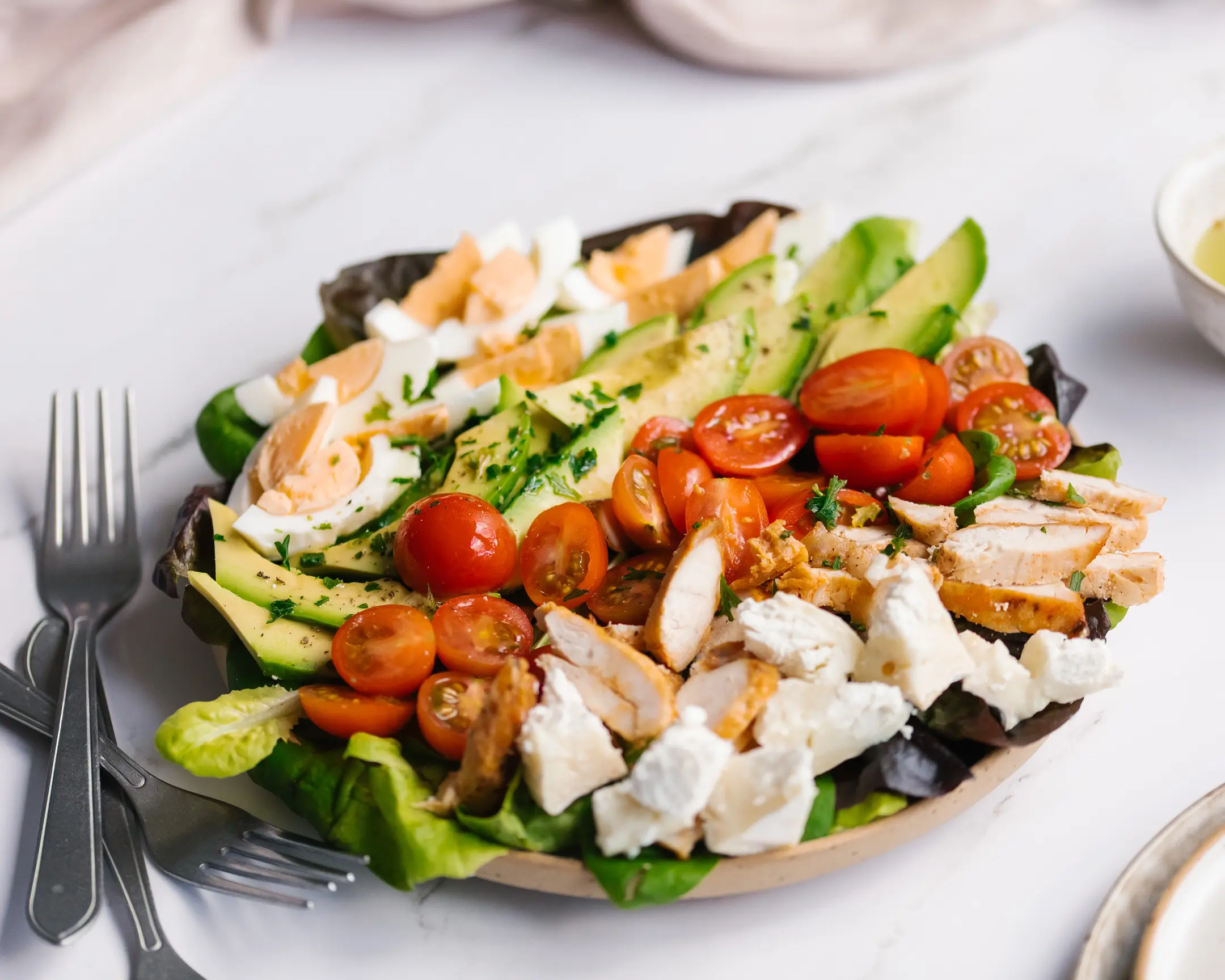 Авторски вариант на салата Коб: пиле, яйца, авокадо, чери домати, козе сирене и свежи зелении.
