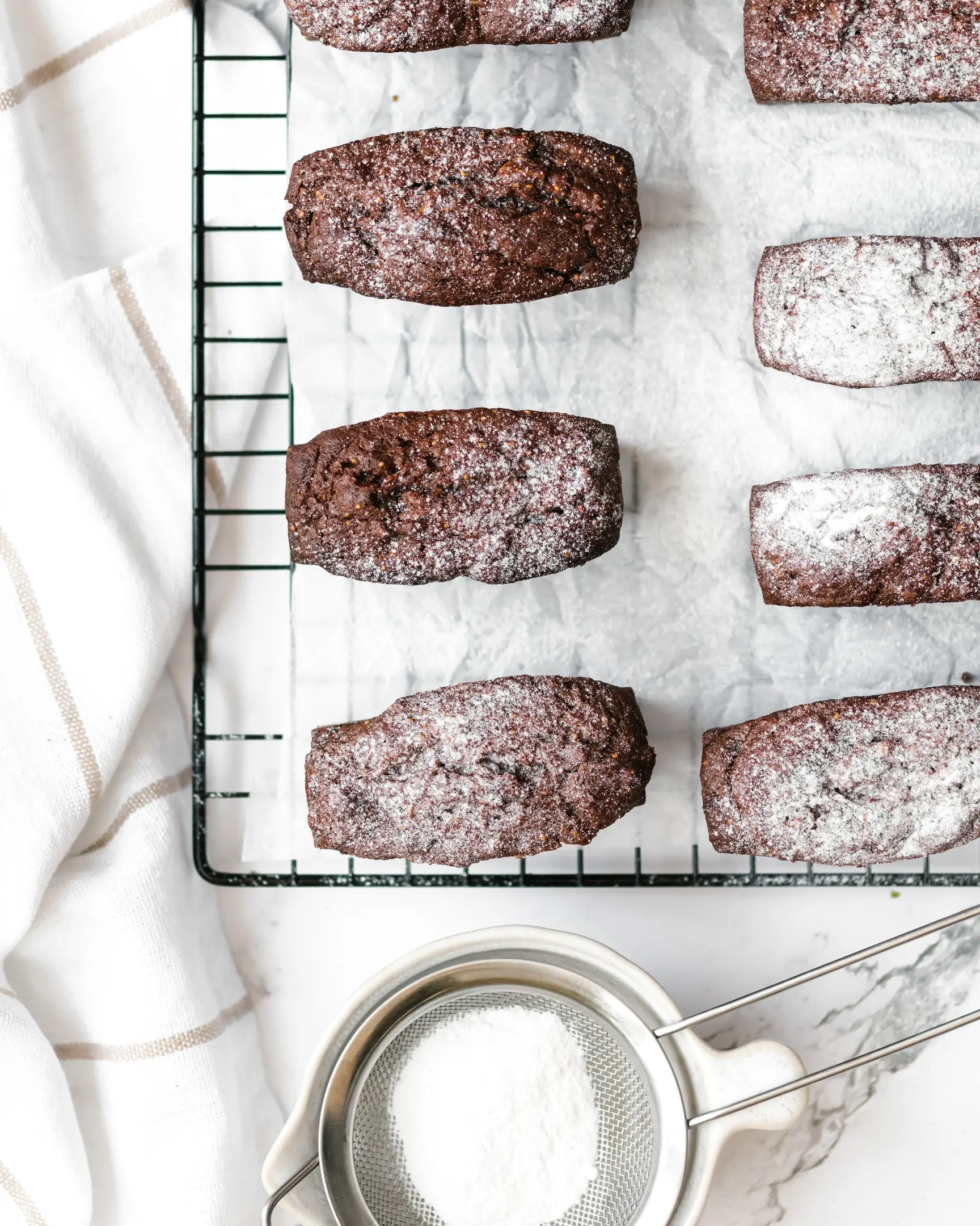 Новоизпечени кексчета на Оля със смокини и фурми, върху решетка, поръсени с пудра захар.