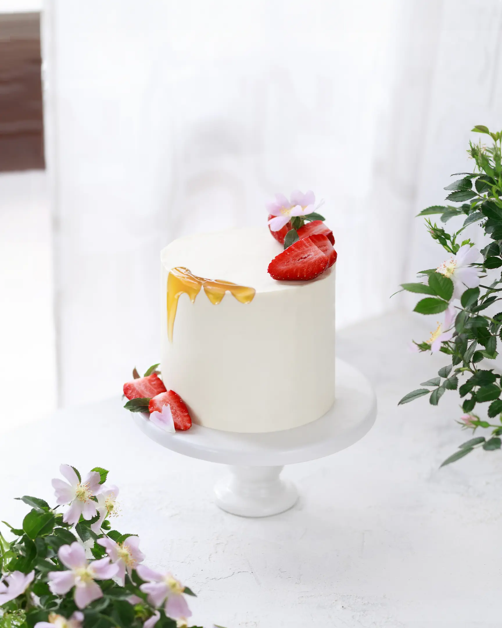 Honey cake with white cream frosting, fresh strawberries, and golden honey drizzle. Perfect dessert recipe.