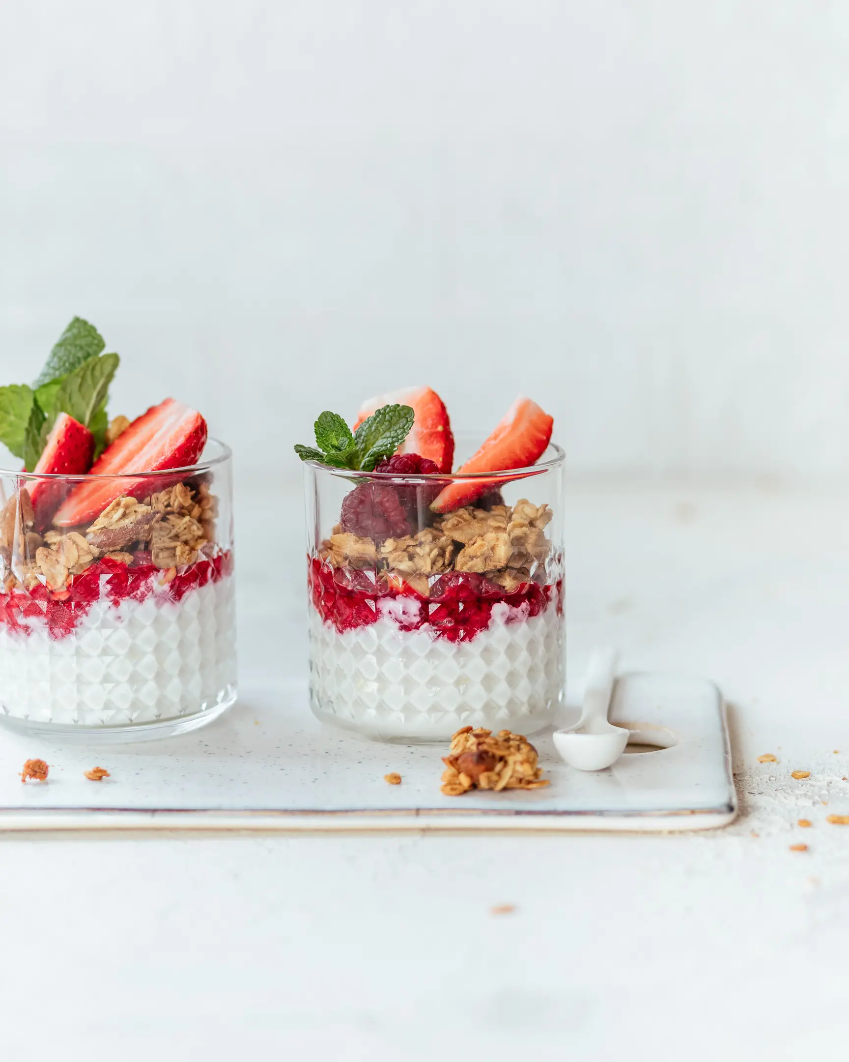 Homemade banana granola parfaits with yogurt, berries, strawberries & mint. Healthy breakfast.