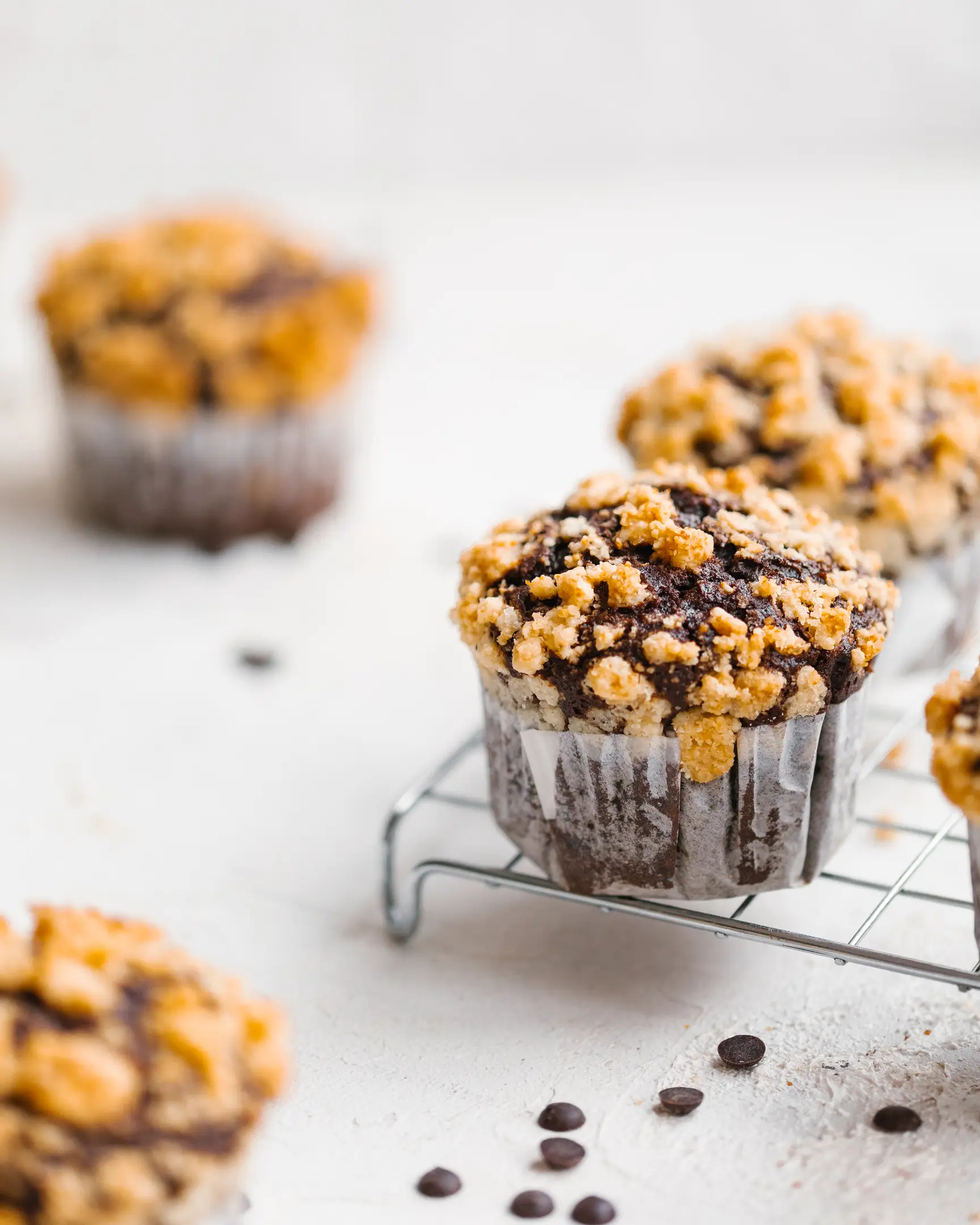 Baked pumpkin chocolate cupcakes with golden crumble topping, cooling on a rack.