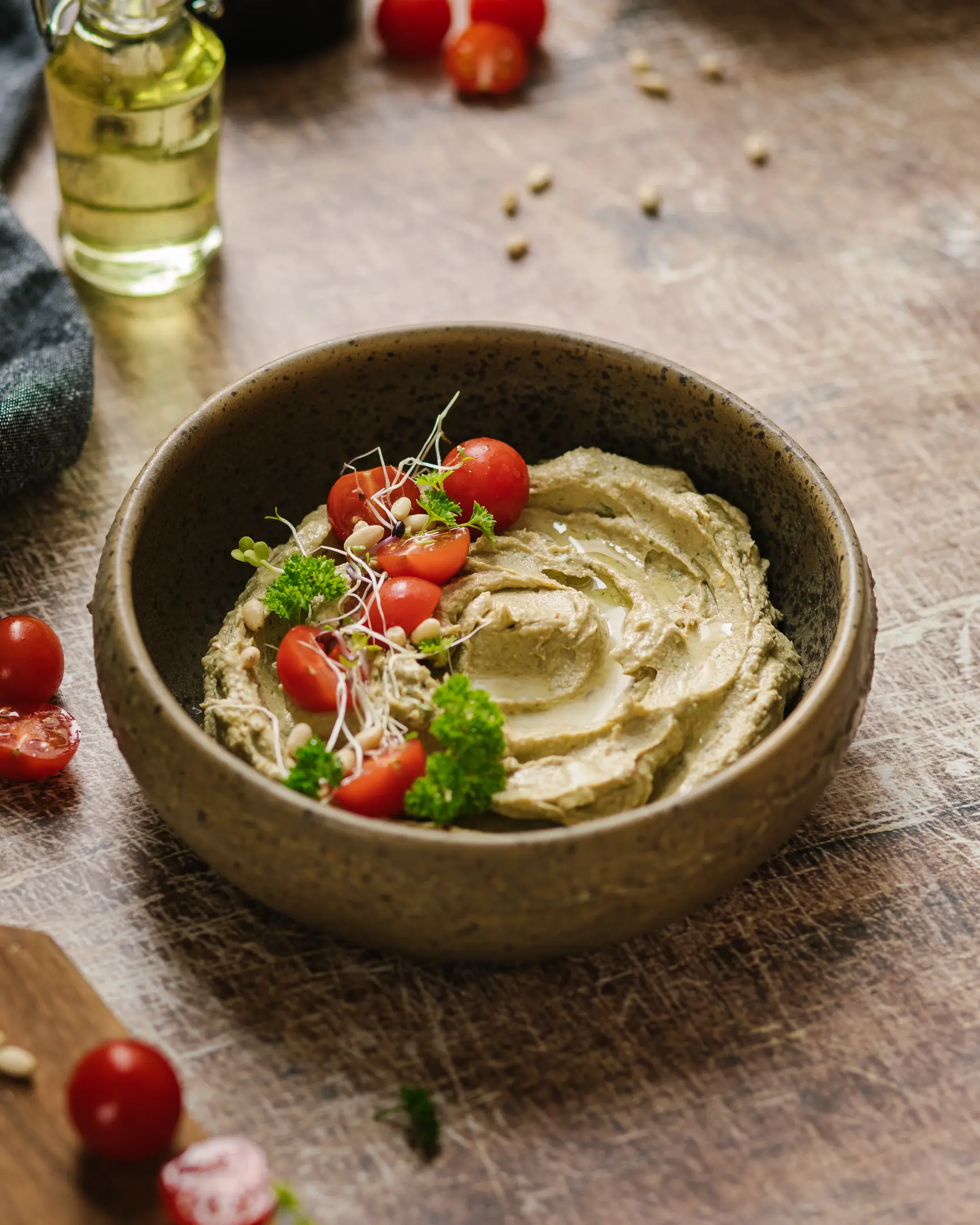 Silky homemade avocado hummus with olive oil, microgreens, pine nuts & cherry tomatoes, ready to serve.