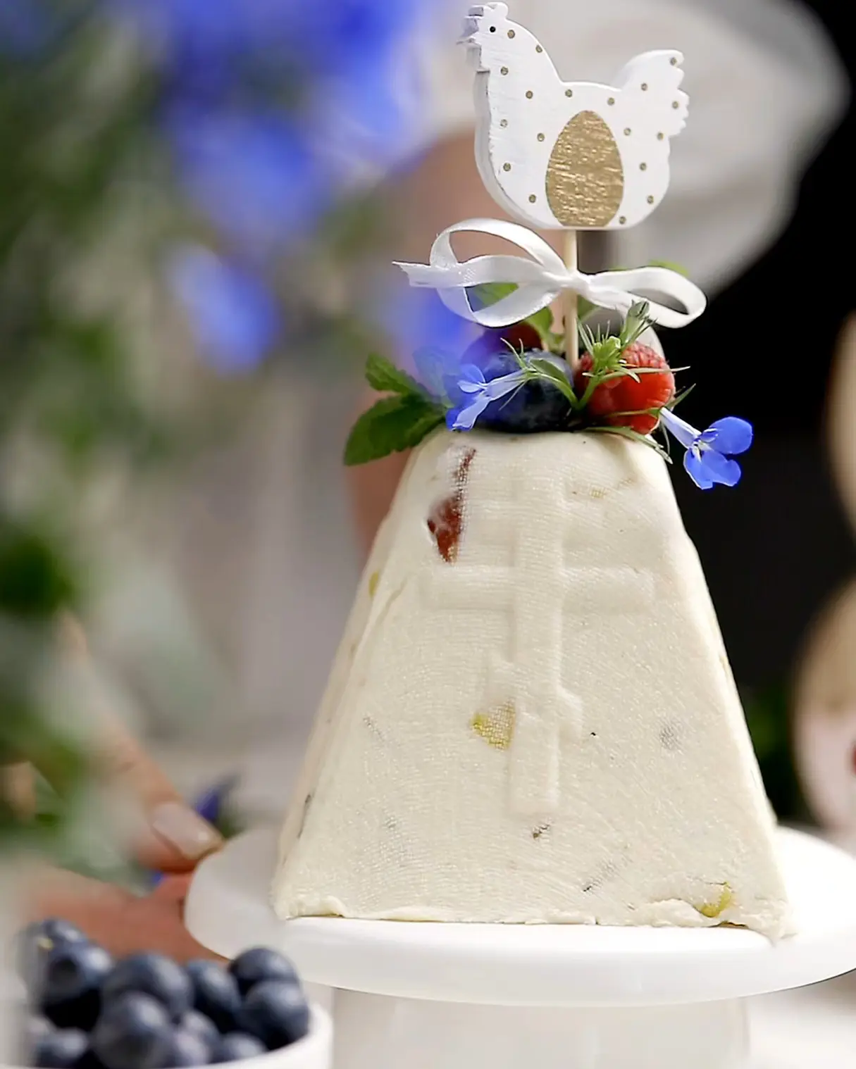 Pyramid-shaped Cottage Cheese Easter Dessert, decorated with fresh berries, mint, and a chicken topper, featuring candied fruits.