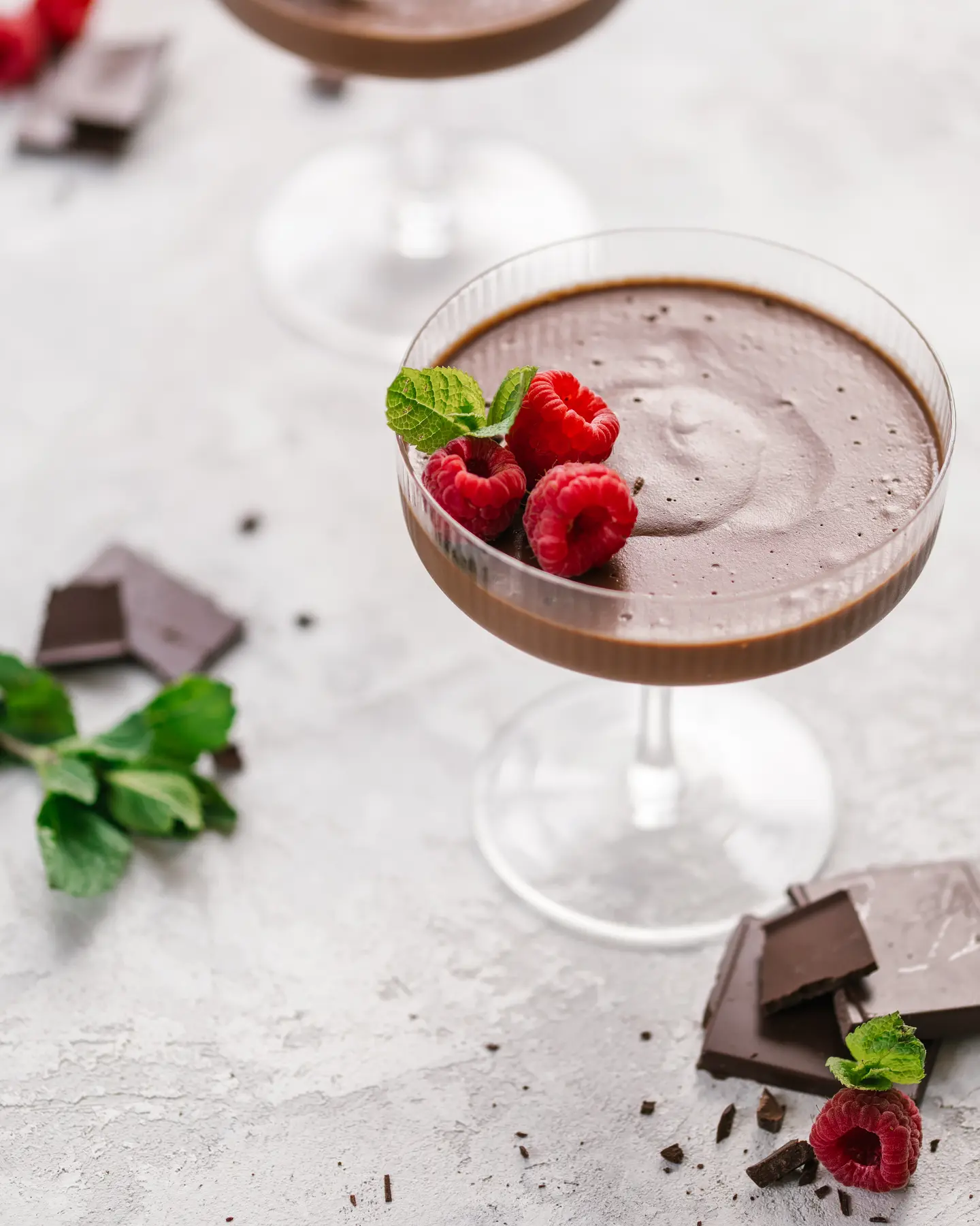 Dark chocolate plant-based mousse with raspberries & mint in a glass; no refined sugar dessert.