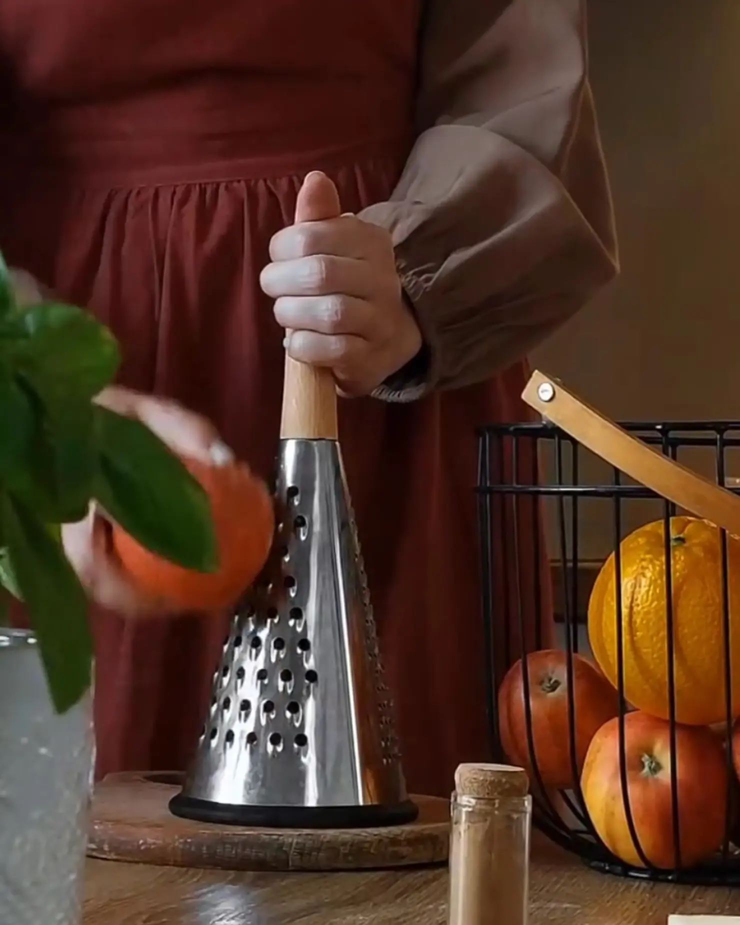 Hands grating apples for the Lazy Layered Pie recipe, with a cinnamon jar and fresh fruit.