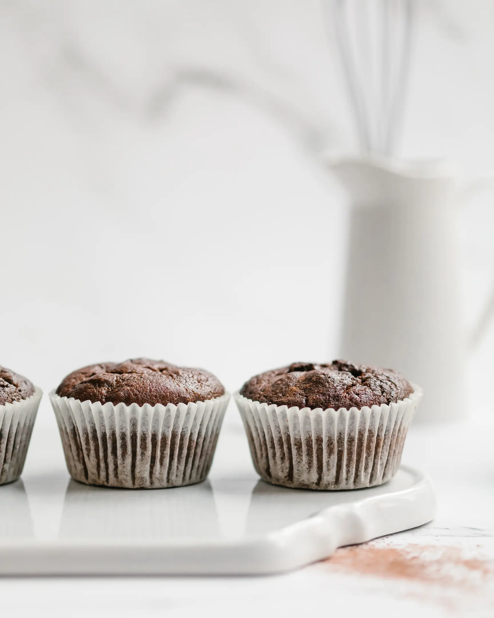 Healthy dark chocolate banana muffins (no flour, no sugar) on a white tray, offering PMS relief & women's health benefits.