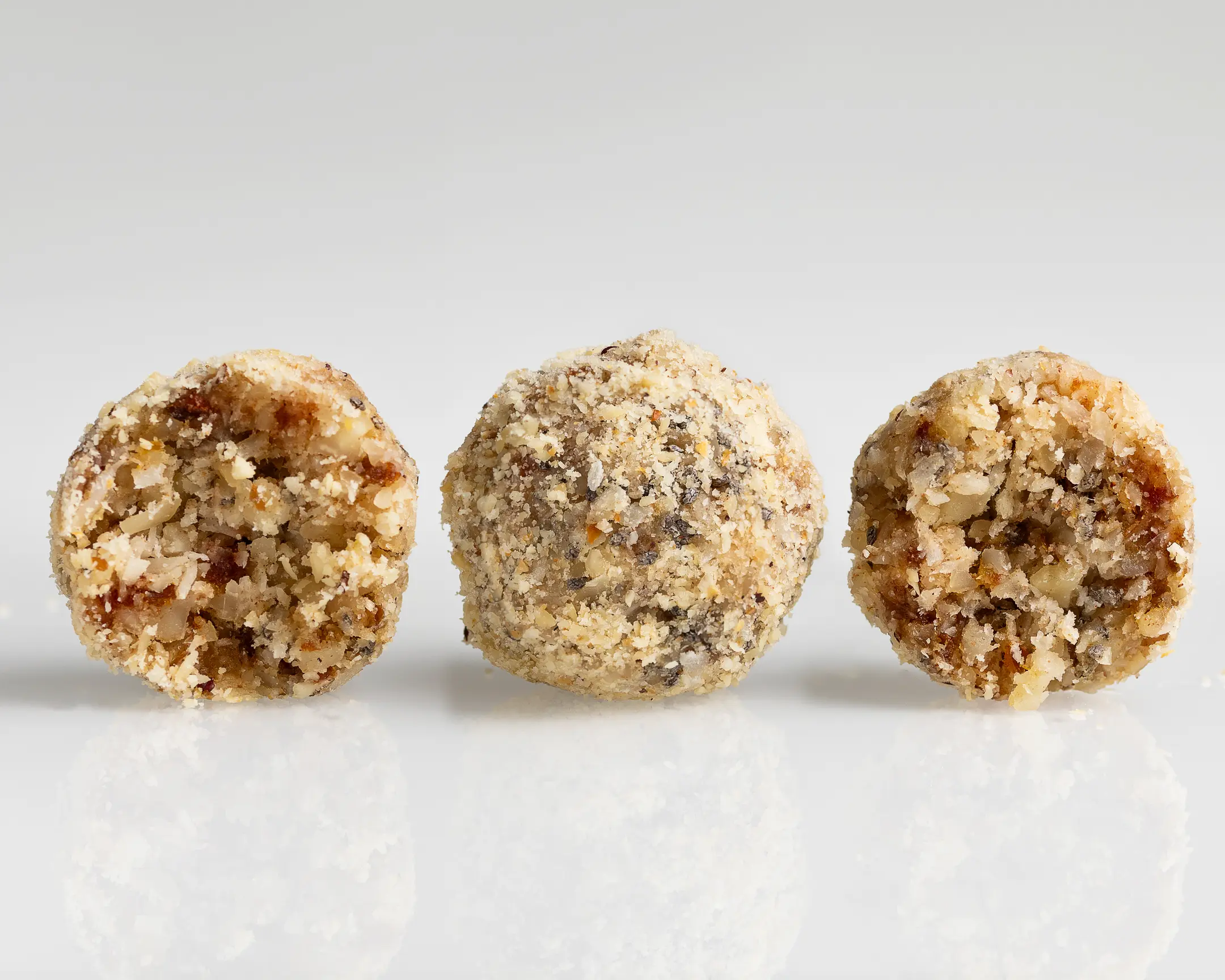 Three healthy, sugar-free Almond-Apricot Candies coated in nuts & coconut, ideal for a natural breakfast.