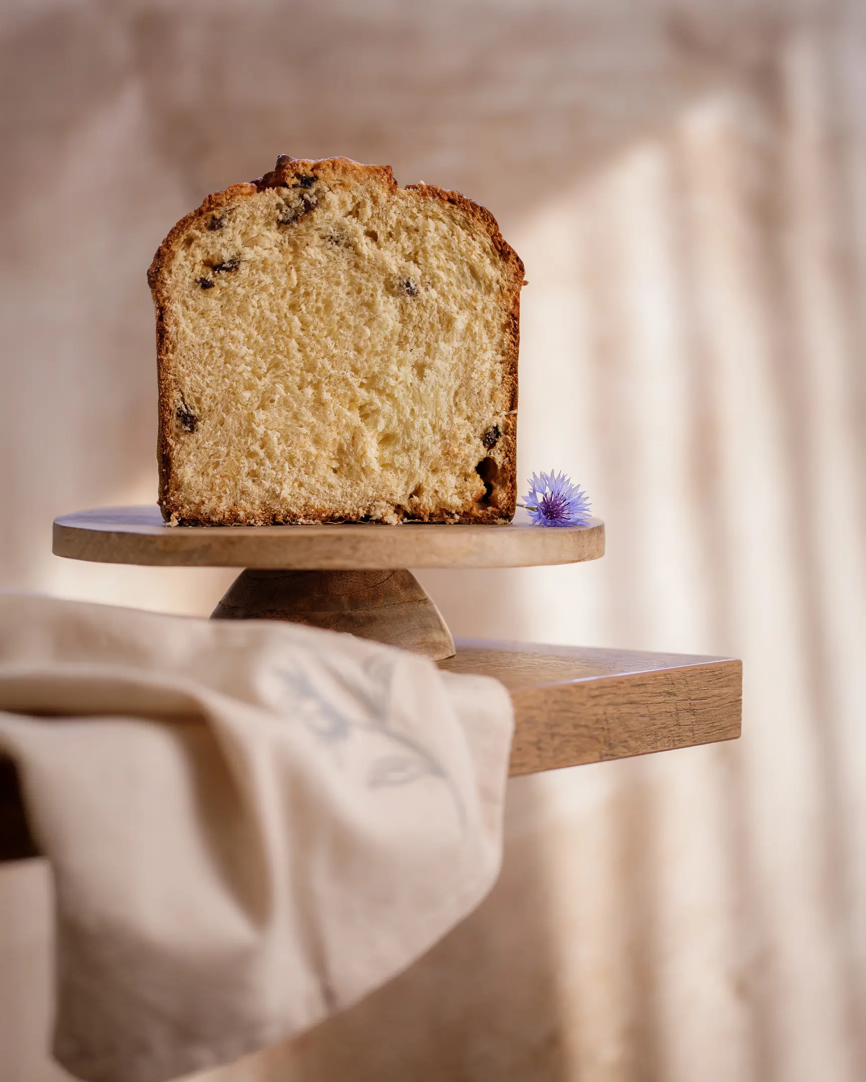 Freshly baked kulich slice, showcasing fluffy texture & candied fruit from delayed salt & butter application.